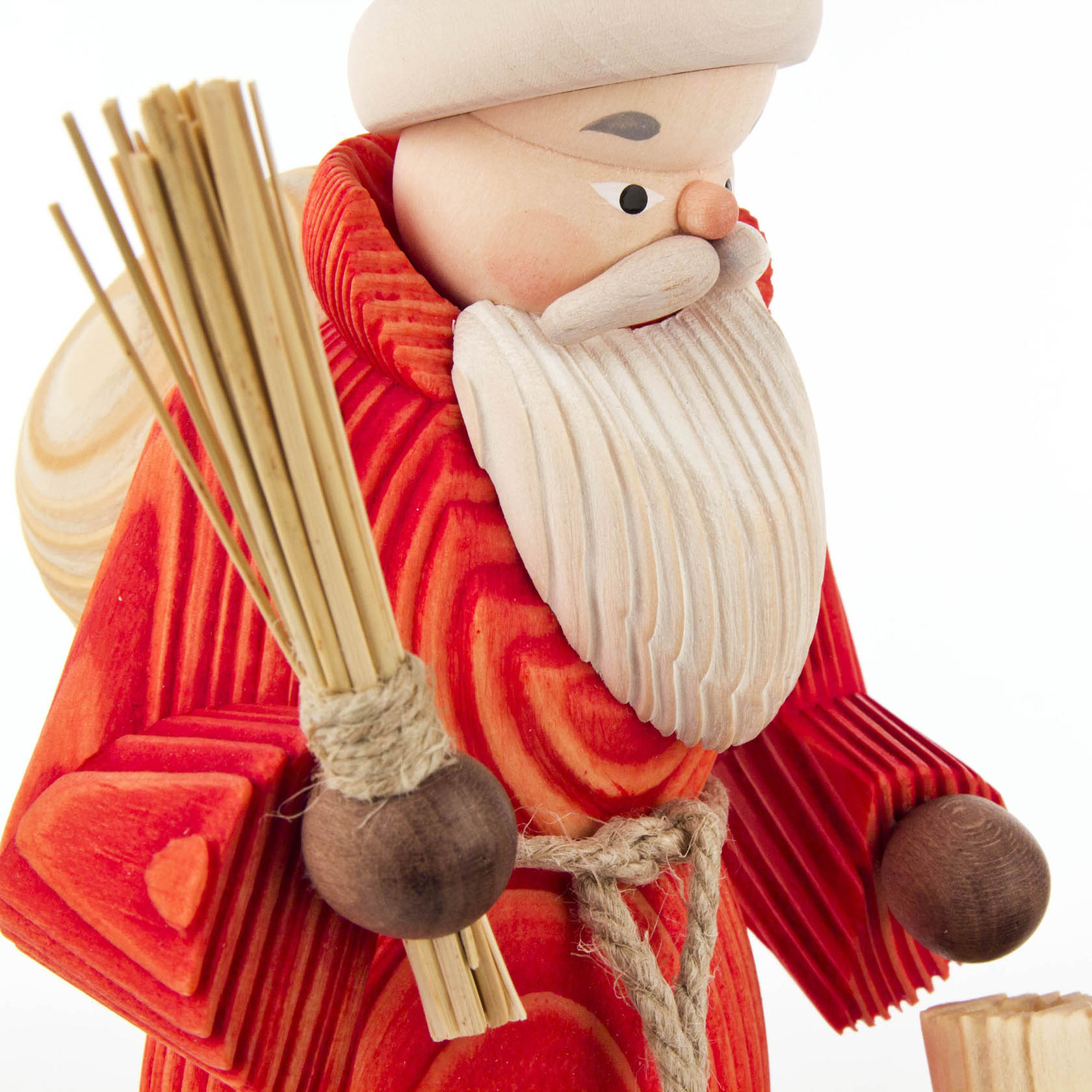 Ein hölzerner Räuchermann in Form eines Weihnachtsmannes, mit rotem gebürsteten Mantel, einem weißen Bart, einem Sack auf dem Rücken und einem Reisigbesen in der Hand.