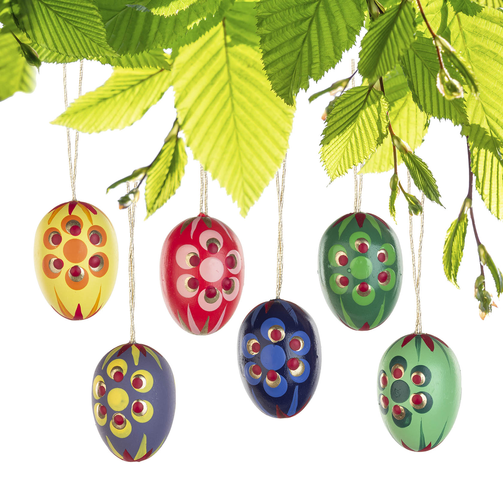 Sechs bemalte Ostereier hängen an Fäden unter grünen Blättern. Die Eier sind in verschiedenen Farben mit floralen Mustern bemalt.