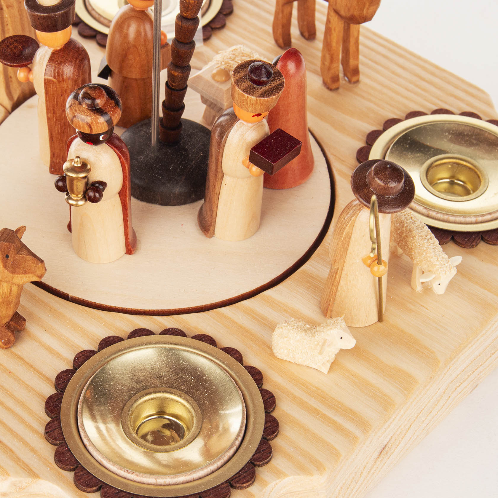 Detailaufnahme einer handgefertigten Holzpyramide zur Darstellung der Geburt Christi, mit Figuren der Heiligen Drei Könige und Kerzenhaltern.