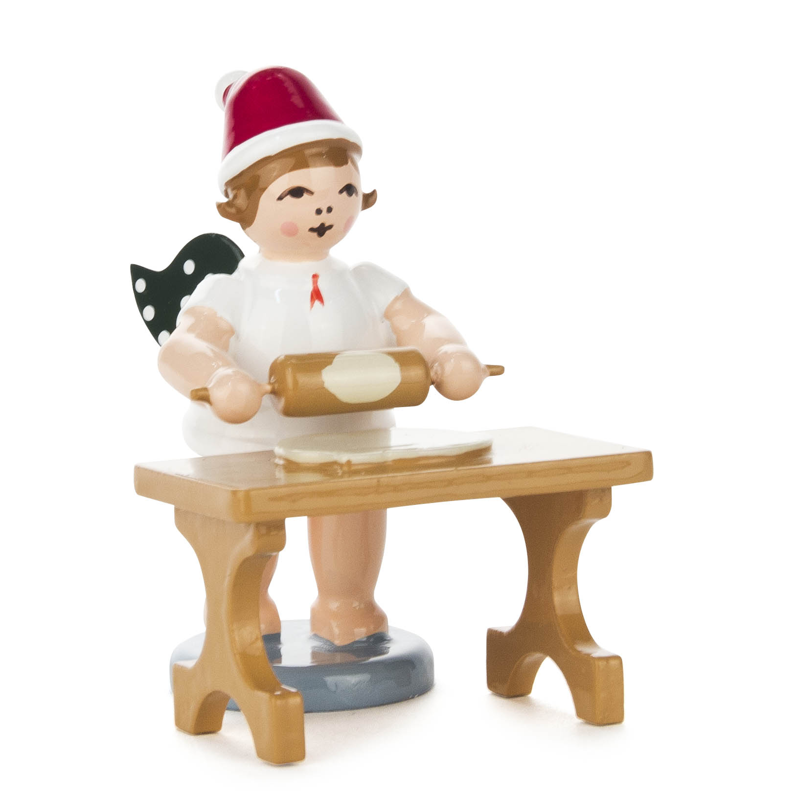 Kleiner Bäckerengel mit roter Mütze, Engelsflügeln und weißem Gewand, der an einem Tisch stehend eine Teigrolle hält. im Dregeno Online Shop günstig kaufen