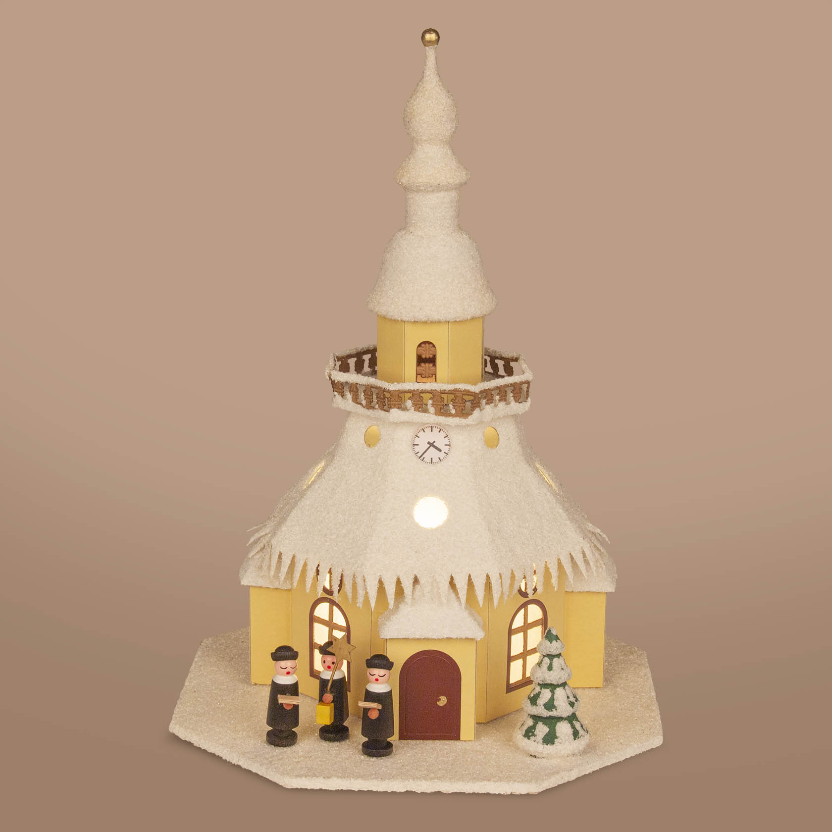 Ein handgefertigtes Modell der Seiffener Kirche mit einer elektrischen Beleuchtung. Vor der Kirche stehen drei Holzfiguren, daneben ein kleiner Tannenbaum.