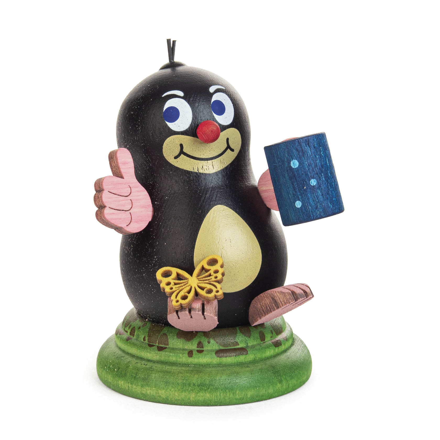 A cartoon mole figurine with a black body, pink feet, hands, and ears, holding a blue book and a thumbs-up gesture, sitting on a green base. im Dregeno Online Shop günstig kaufen