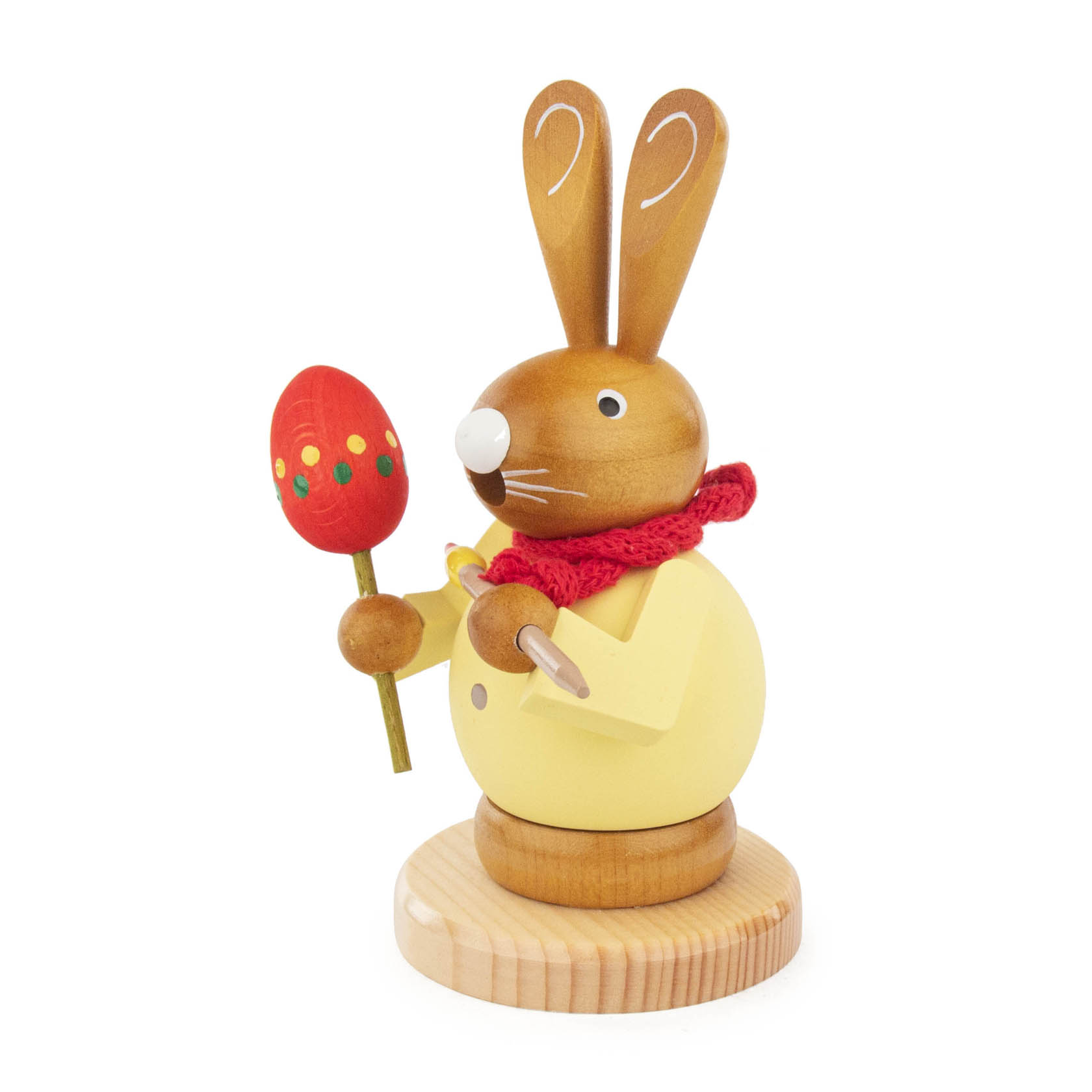 Holzrächfigur eines Hasen mit gelbem Mantel und rotem Schal, der ein bunt bemaltes Ei auf einem Stock hält und einen Pinsel in der anderen Hand. im Dregeno Online Shop günstig kaufen