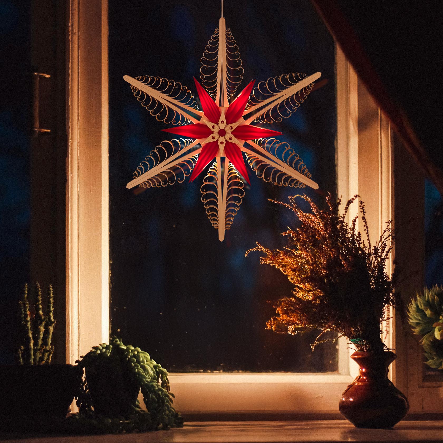 Fensterbild mit einem natur-roten Spanstern, beleuchtet, hängend im Fenster. Umgeben von Blumen und Pflanzen auf der Fensterbank.