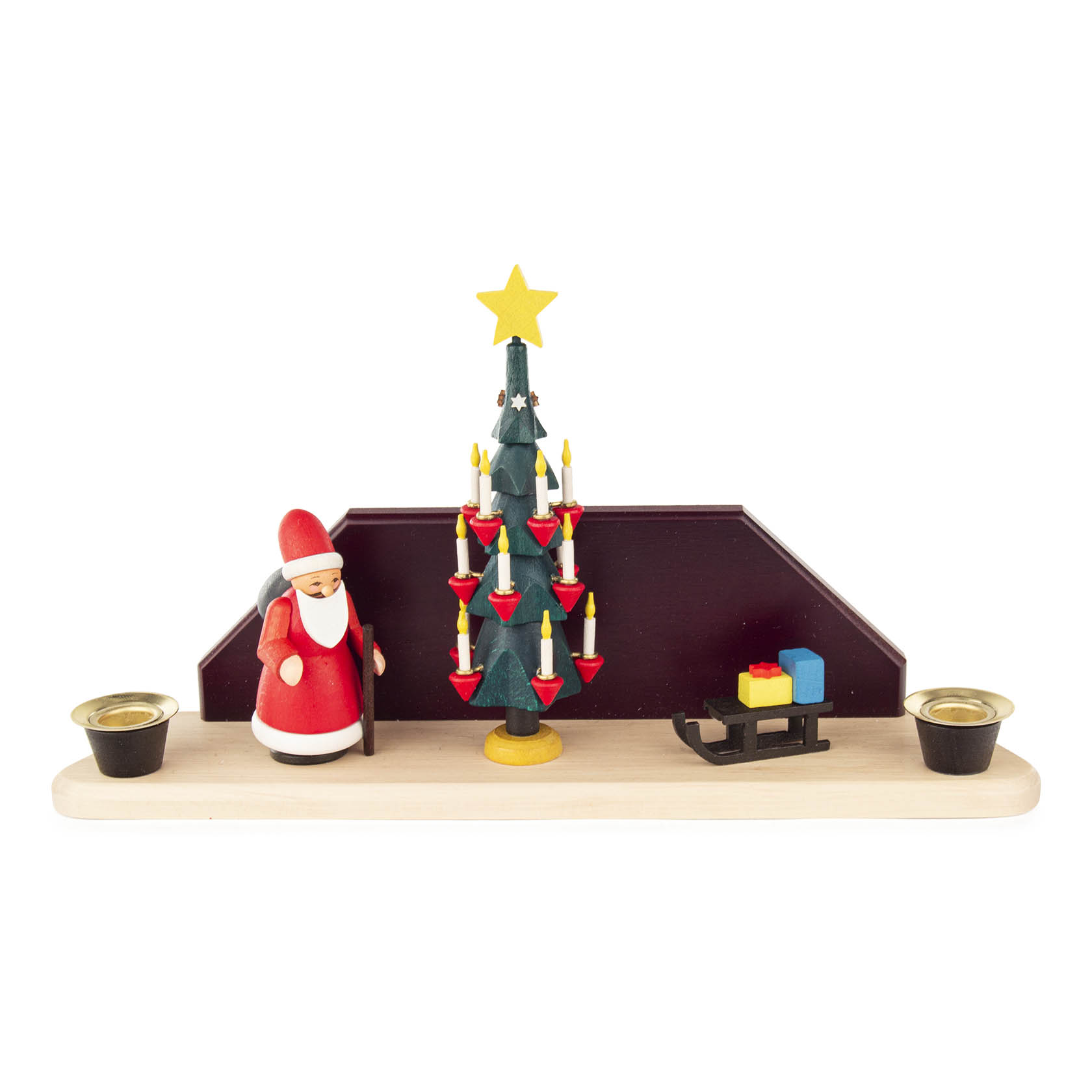 Holzdekoration mit Weihnachtsbaum mit Kerzen, Weihnachtsmannfigur und Schlitten mit Geschenken auf einem Brett. Zwei Teelichthalter links und rechts. im Dregeno Online Shop günstig kaufen