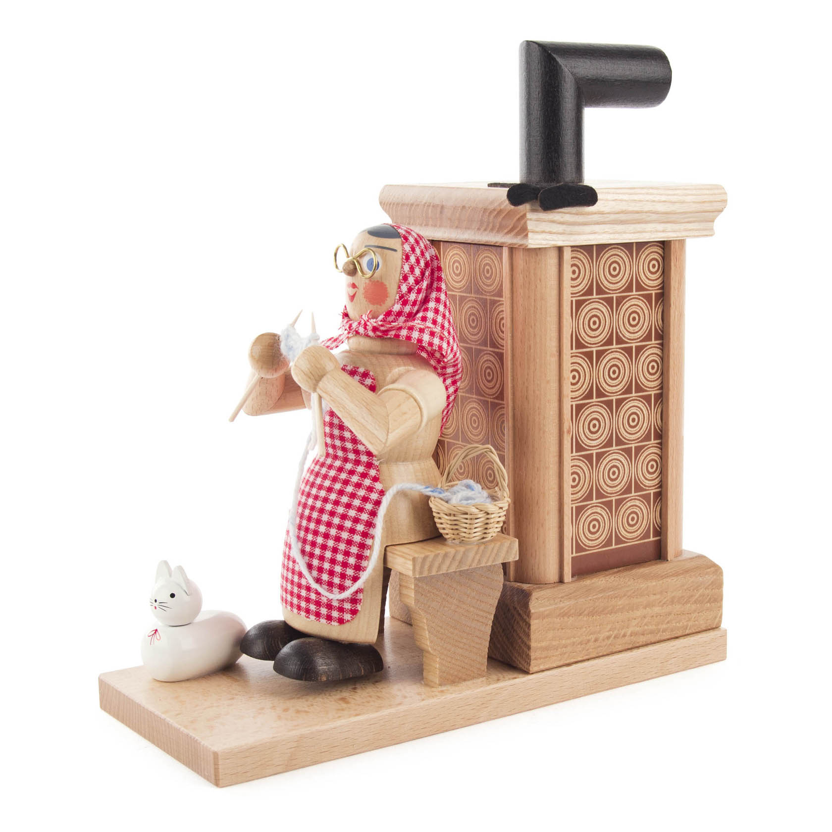 Holzfigur einer Oma mit Kopftuch sitzt auf einer Ofenbank eines Räucherofens, eine Katze sitzt davor.