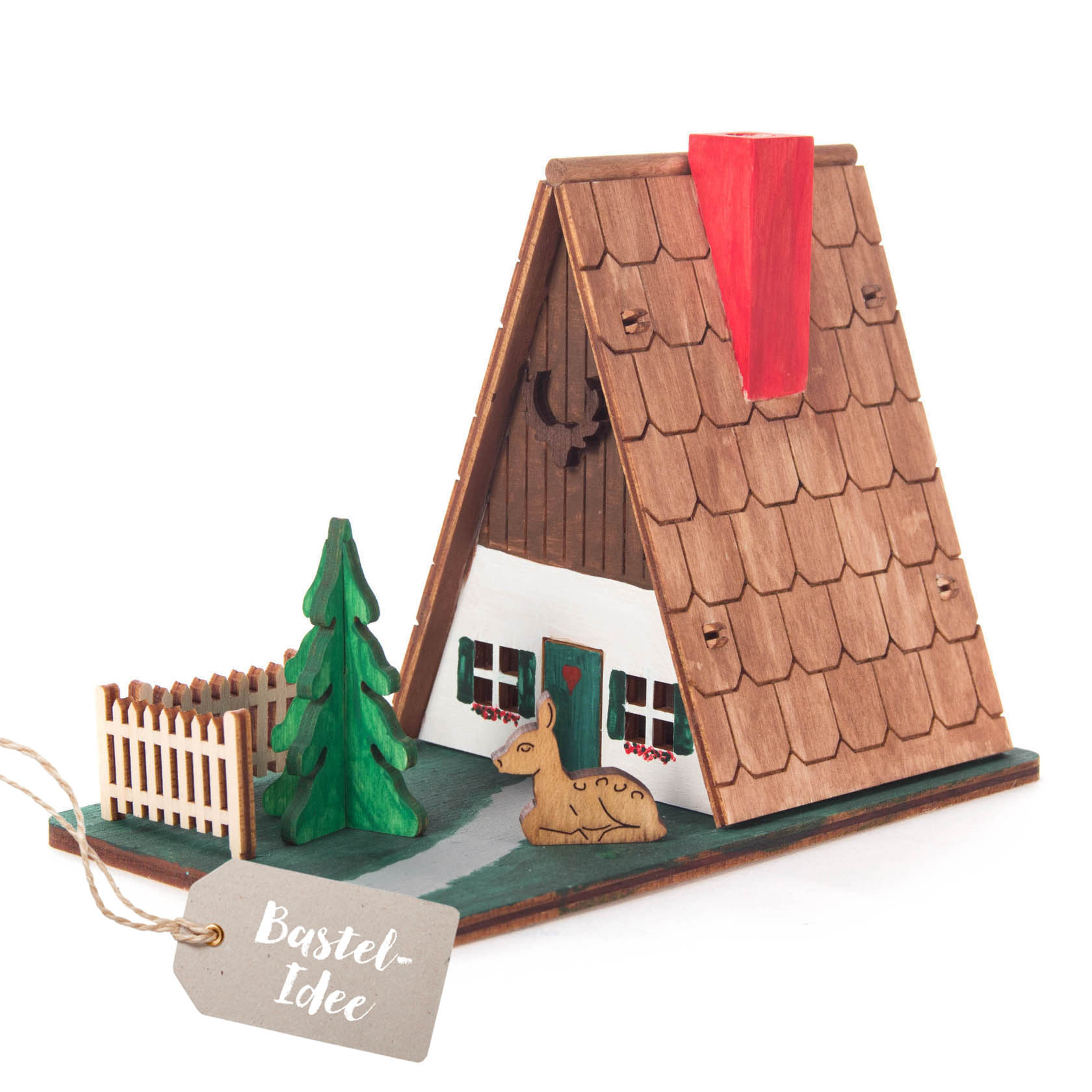 Ein Bastelset mit einem kleinen Forsthaus aus Holz mit rotem Schornstein, grüner Tanne, kleinem Zaun und Rehfigur. im Dregeno Online Shop günstig kaufen