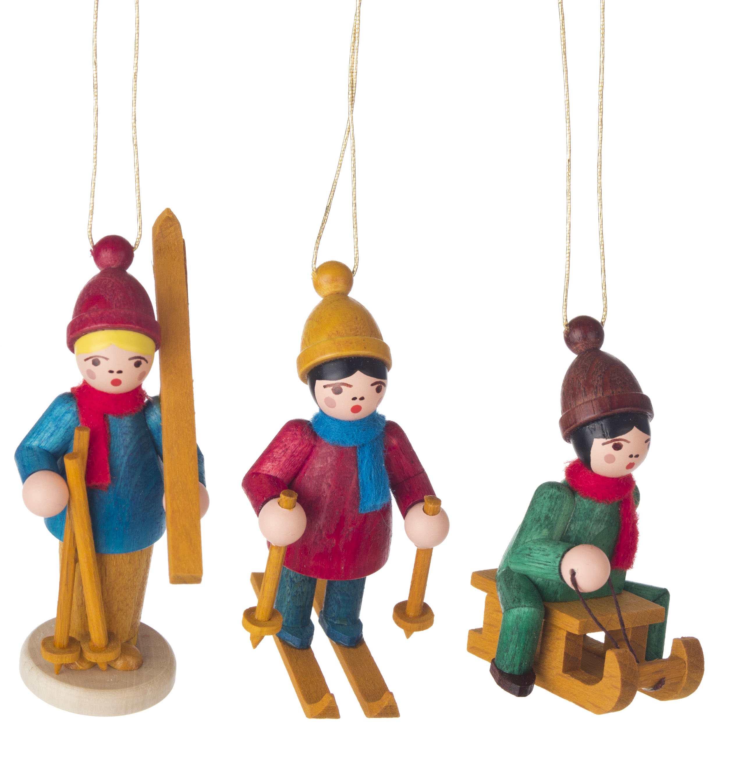 Drei hölzerne Weihnachtsschmuckfiguren von Kindern im Winter, zwei auf Skiern und eines auf einem Schlitten, alle in bunten Winterkleidung.