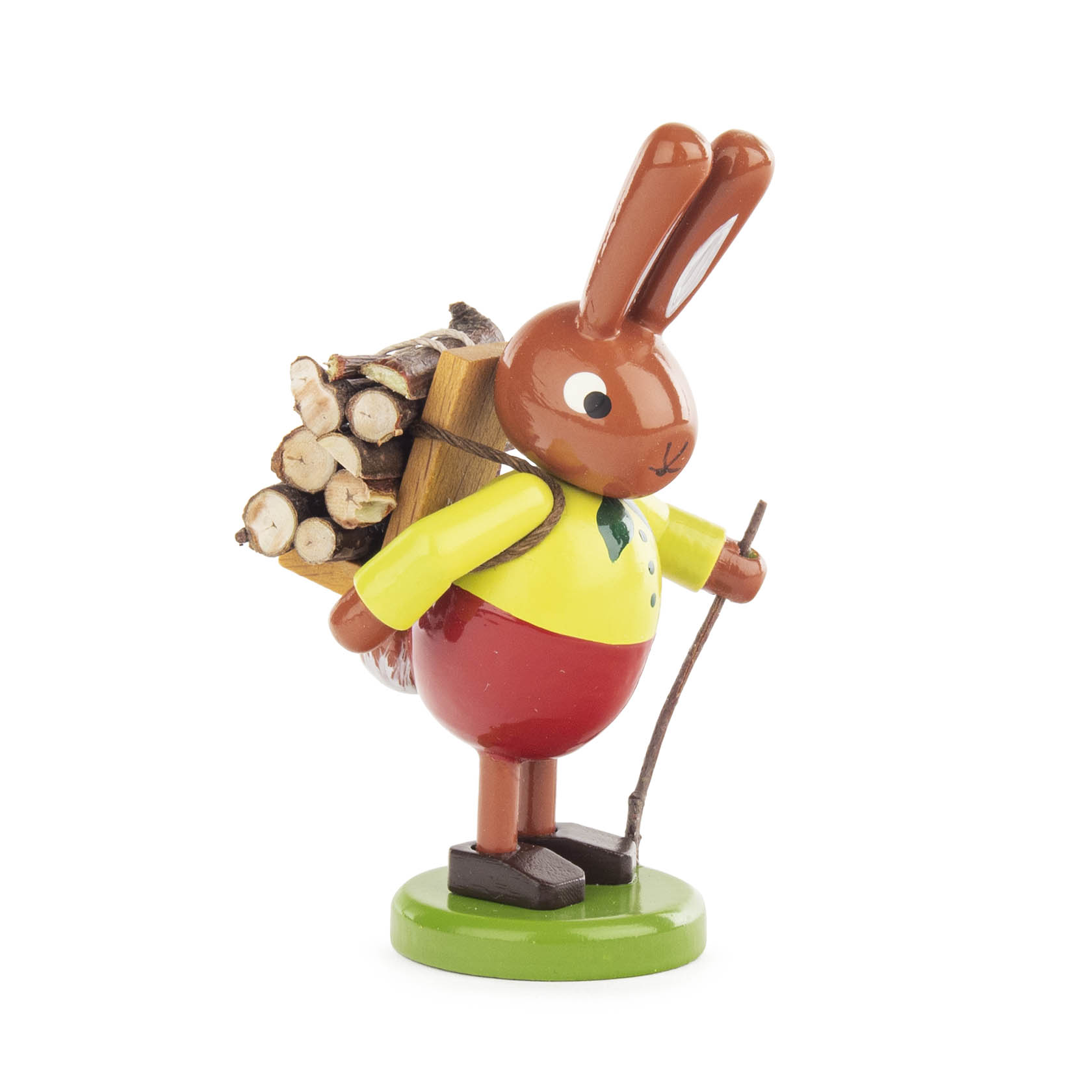 Holzfigur eines Hasen in rotem Rock und gelbem Hemd mit Holztrage auf dem Rücken, stehend auf grünem Sockel. im Dregeno Online Shop günstig kaufen