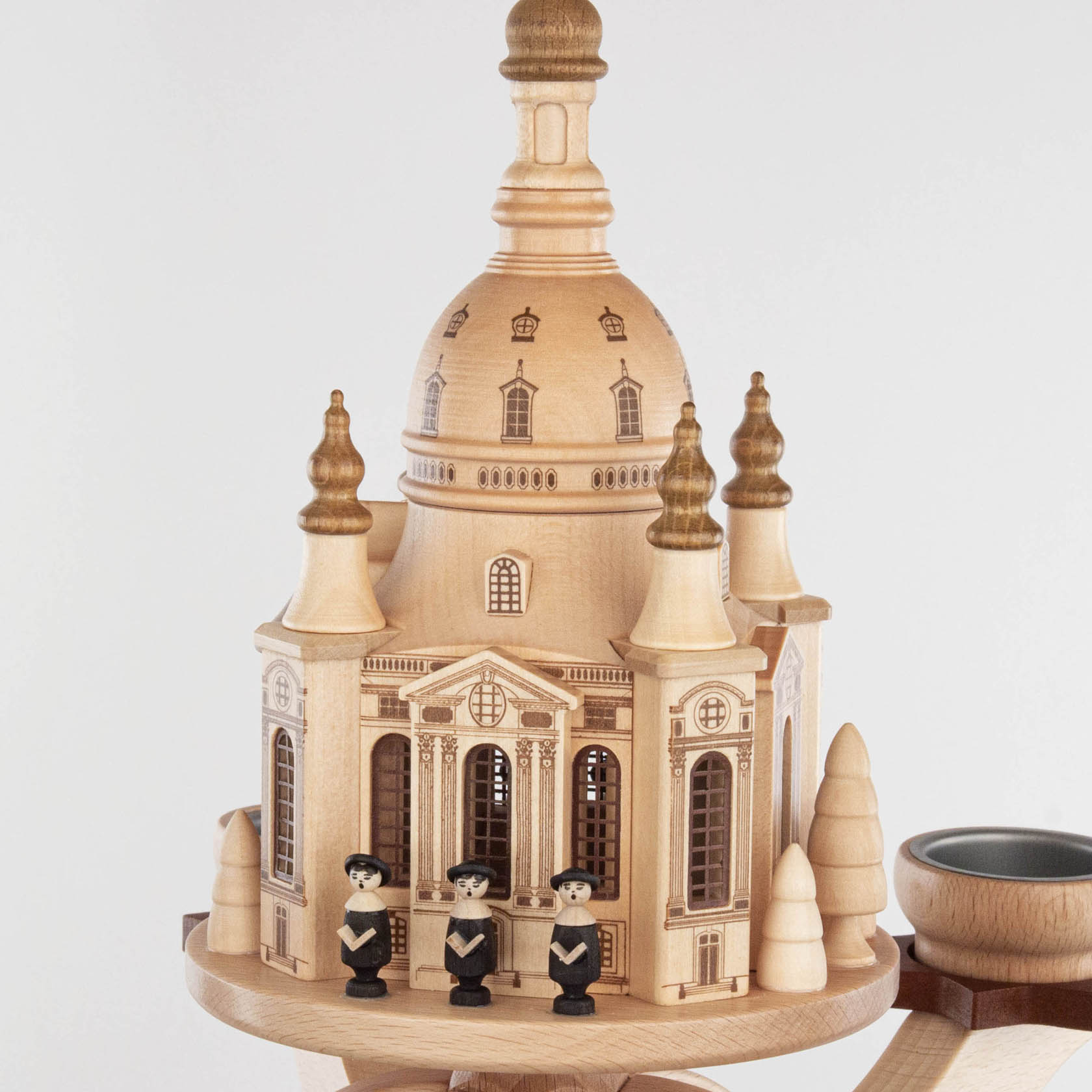Detailreiche Holzpyramide der Dresdner Frauenkirche mit Figuren in traditioneller Tracht und Teelichthalter, dekoriert mit Miniaturbäumen.