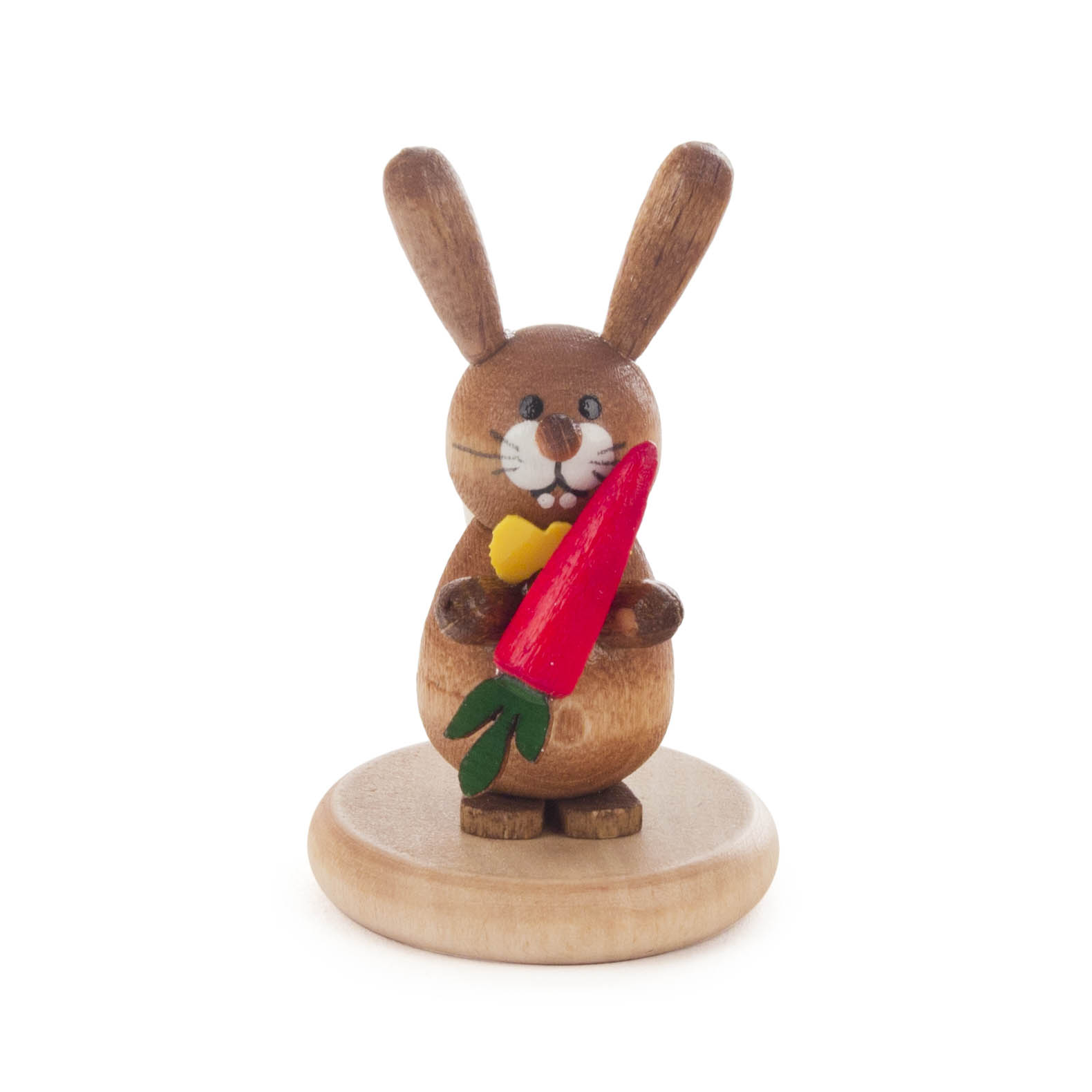 Holzfigur eines sitzenden Hasen mit großer roter Möhre in den Händen auf einem runden Sockel. Der Hase wirkt fröhlich und ist farbig lasiert.