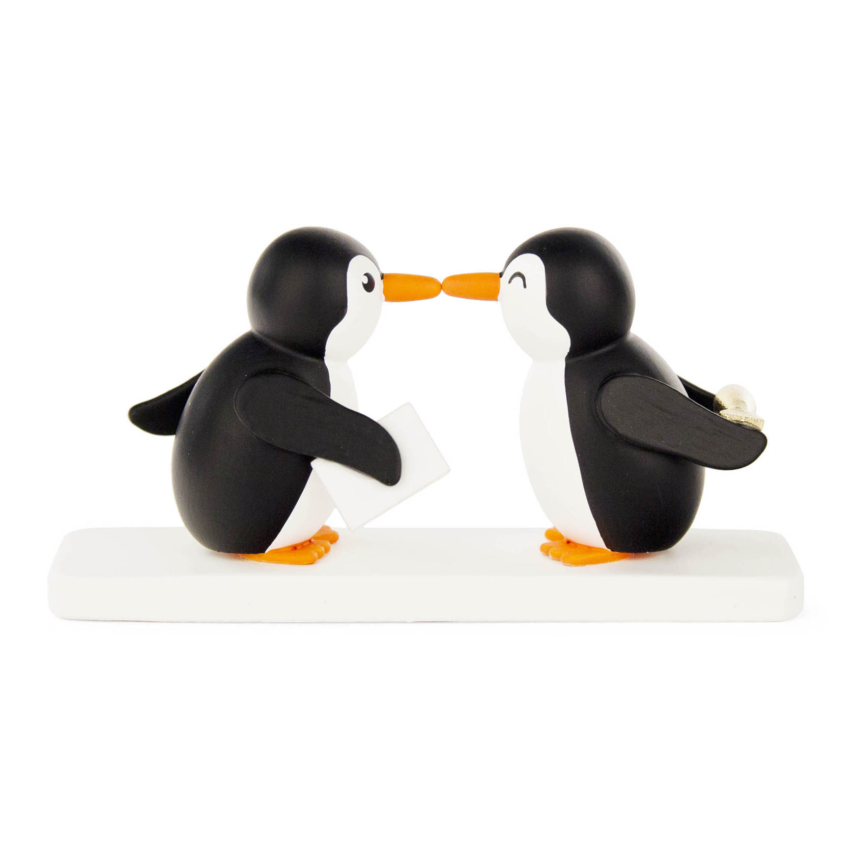 Zwei stilisierte Pinguine stehen sich auf einem weißen Sockel gegenüber, einer hält einen Brief, der andere eine Perle. Sie berühren sich mit den Schnäbeln. im Dregeno Online Shop günstig kaufen