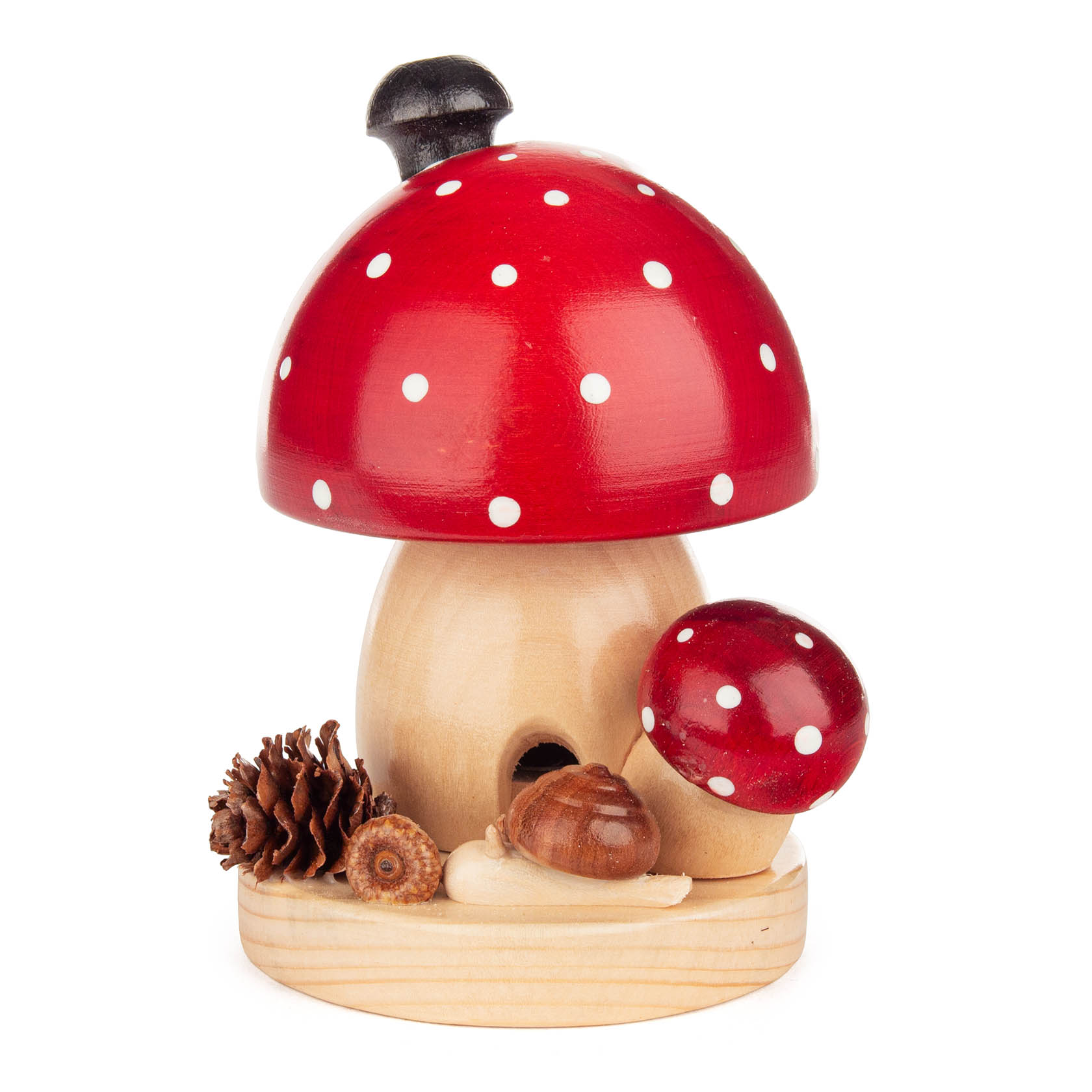 Kleiner, runder Räucherpilz in Form eines Fliegenpilzes mit rotem Punktmuster auf einem Holzsockel, dekoriert mit kleinen Tannen- und Eicheln. im Dregeno Online Shop günstig kaufen