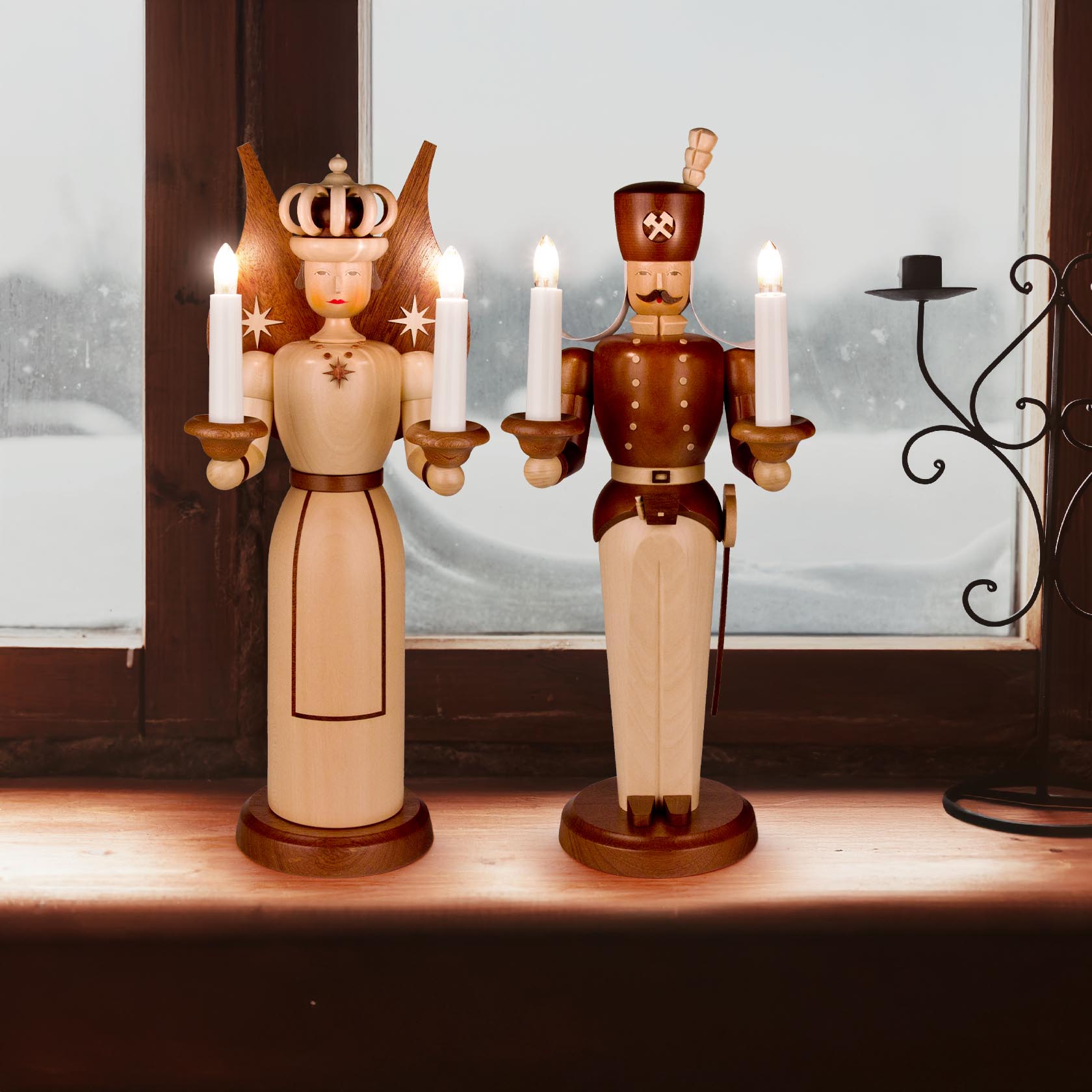 Wooden figures of an angel and a miner, each 40cm tall, are placed on a windowsill. They are electrically lit with transformers and hold candles.