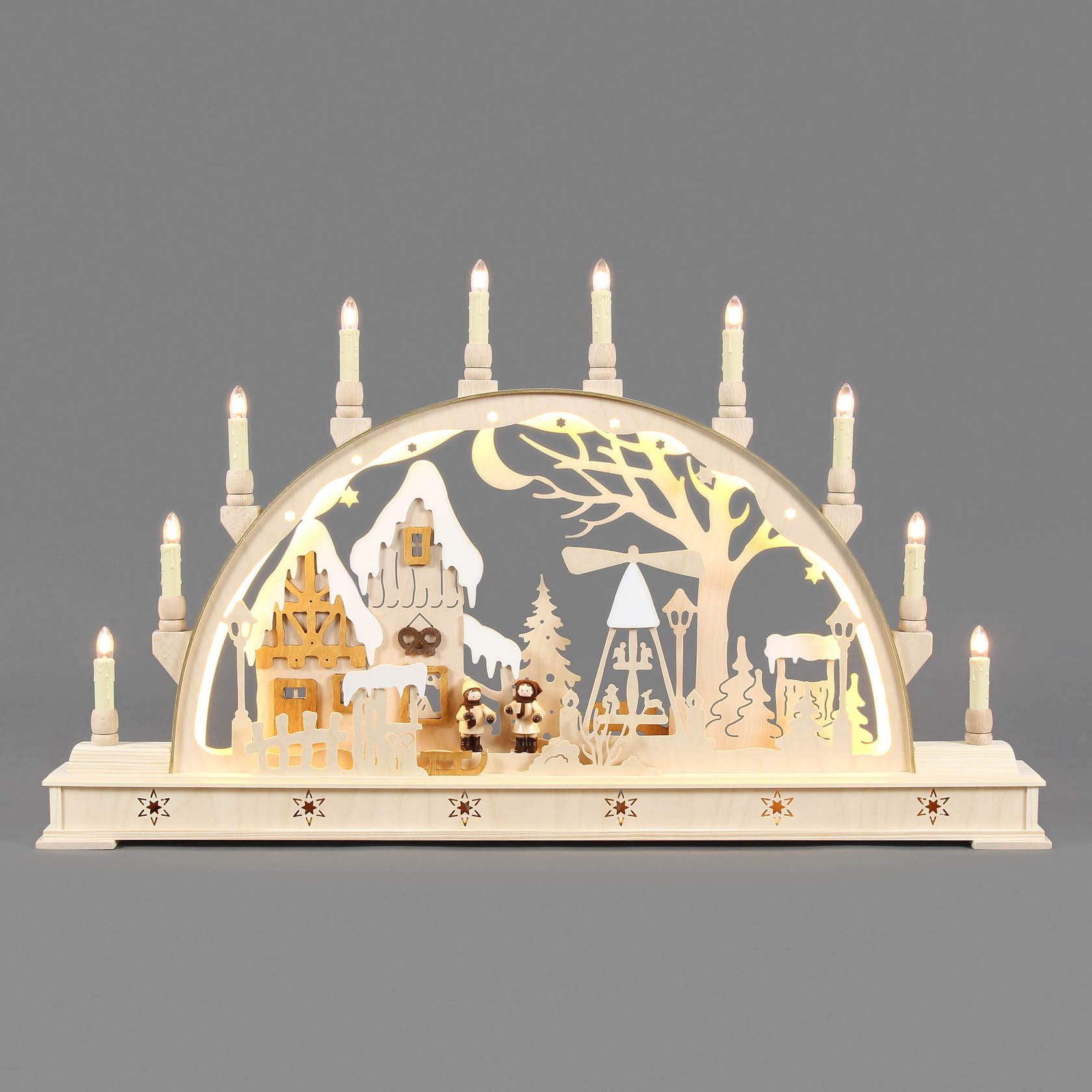 Ein traditioneller Schwibbogen mit Weihnachtsmarktszene, elektrisch beleuchtet. Die Szene zeigt Gebäude, Weihnachtsbäume und Figuren unter einem Bogen mit Lichtern.