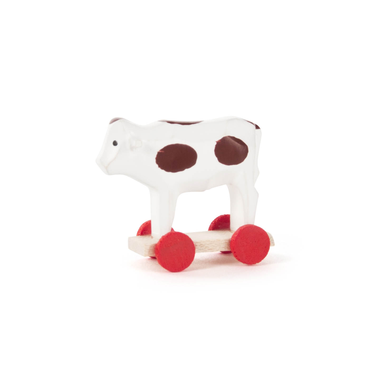 Ein kleines Spielzeug in Form einer Weiß-Braun gefleckten Kuh, die auf vier roten Rädern steht. im Dregeno Online Shop günstig kaufen