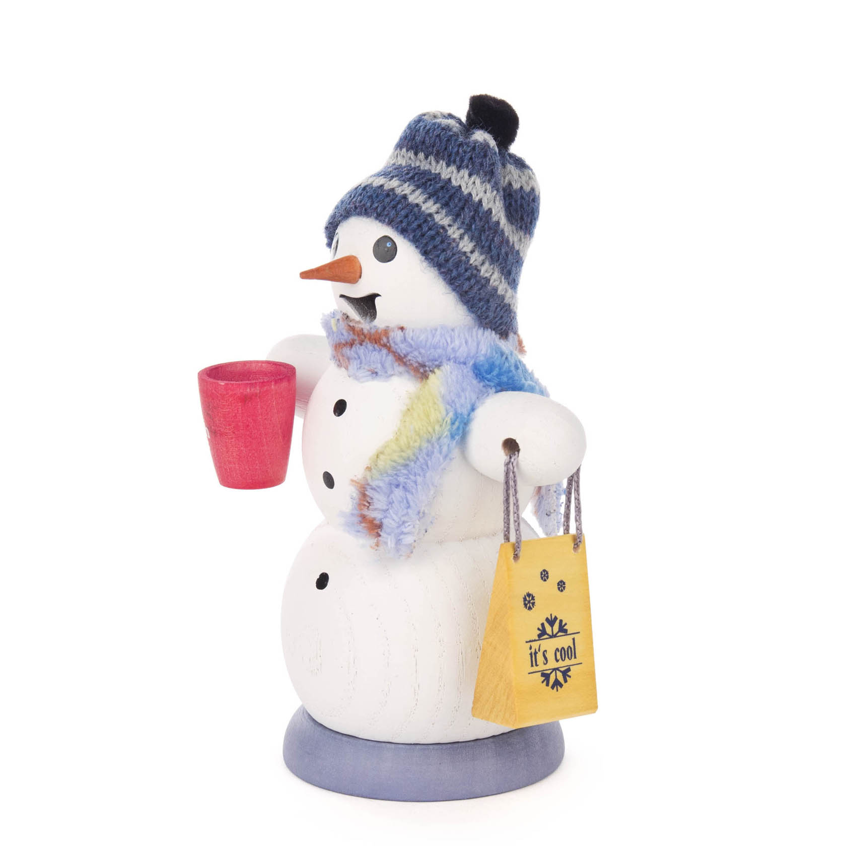 Ein weißer Räuchermann in Form eines Schneemanns mit blauer Mütze und Schal. Er hält eine rote Glühweintasse und eine gelbe Tüte mit der Aufschrift 'it's cool'.