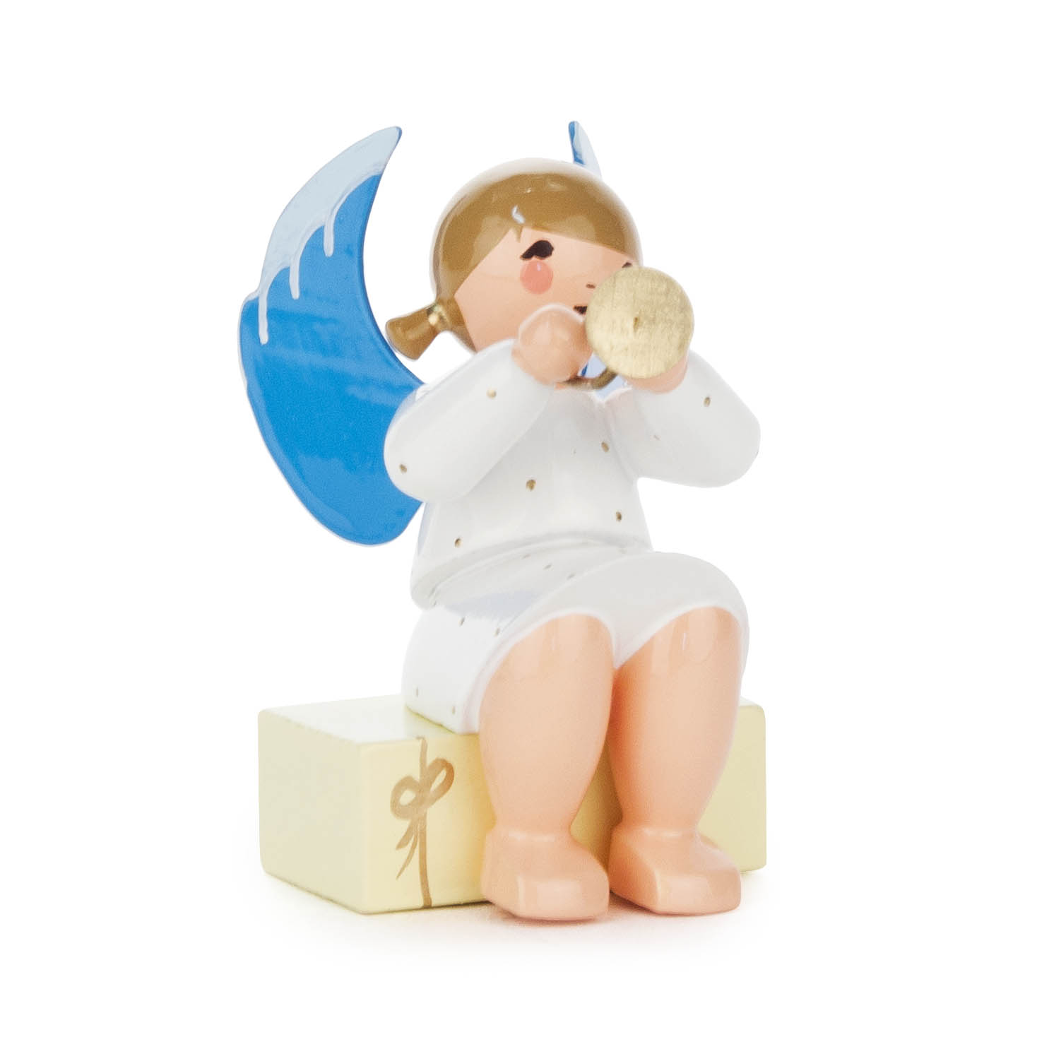 Figur eines Engels mit blauen Flügeln und goldener Trompete, der auf einem gelben Geschenkpaket sitzt und weiße Kleidung trägt.