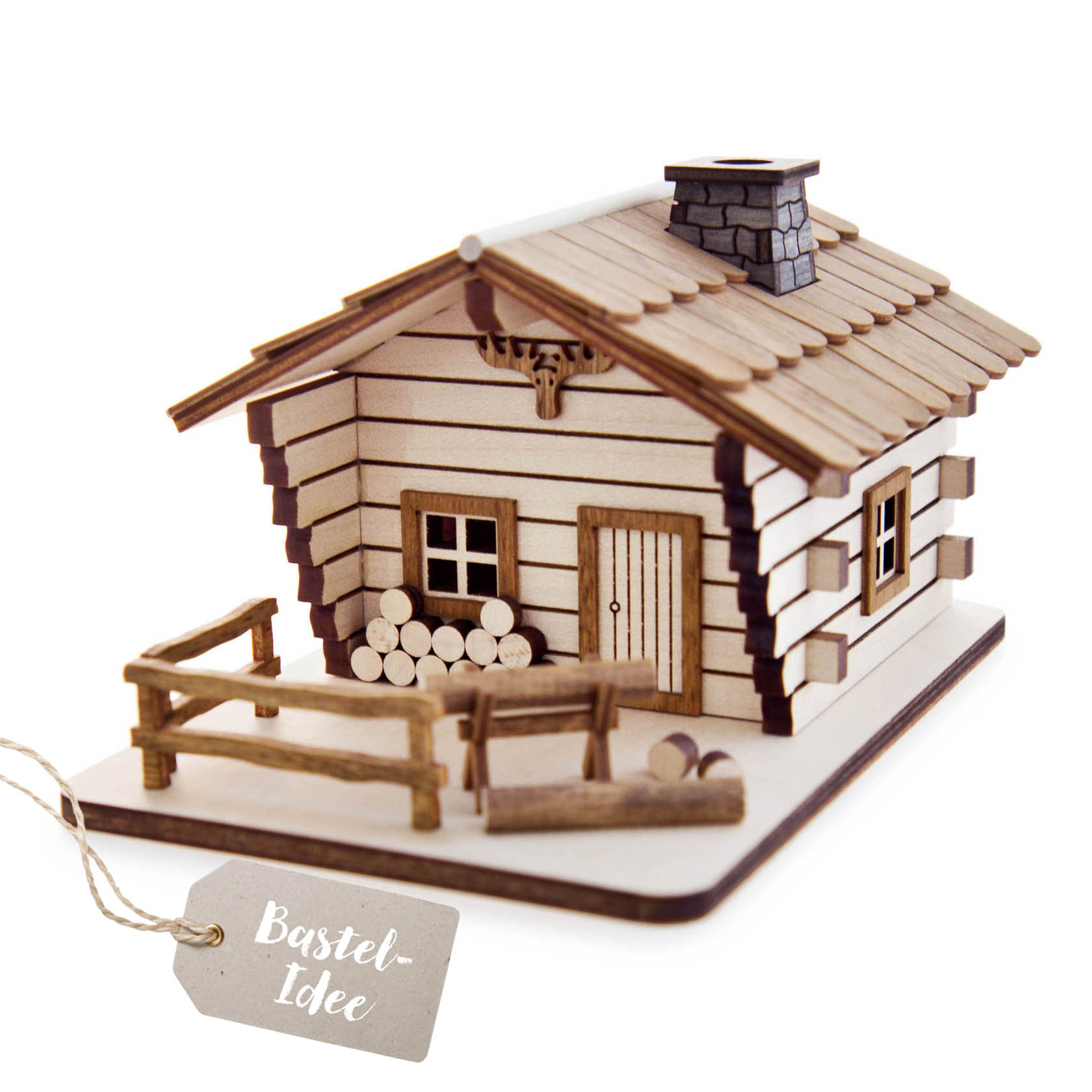 Ein Bastelset eines Räucherhauses in Form einer Blockhütte mit braunen Holzdetails, Kamin und Zaun, dekoriert mit Holzstapeln, auf einer rechteckigen Plattform. im Dregeno Online Shop günstig kaufen