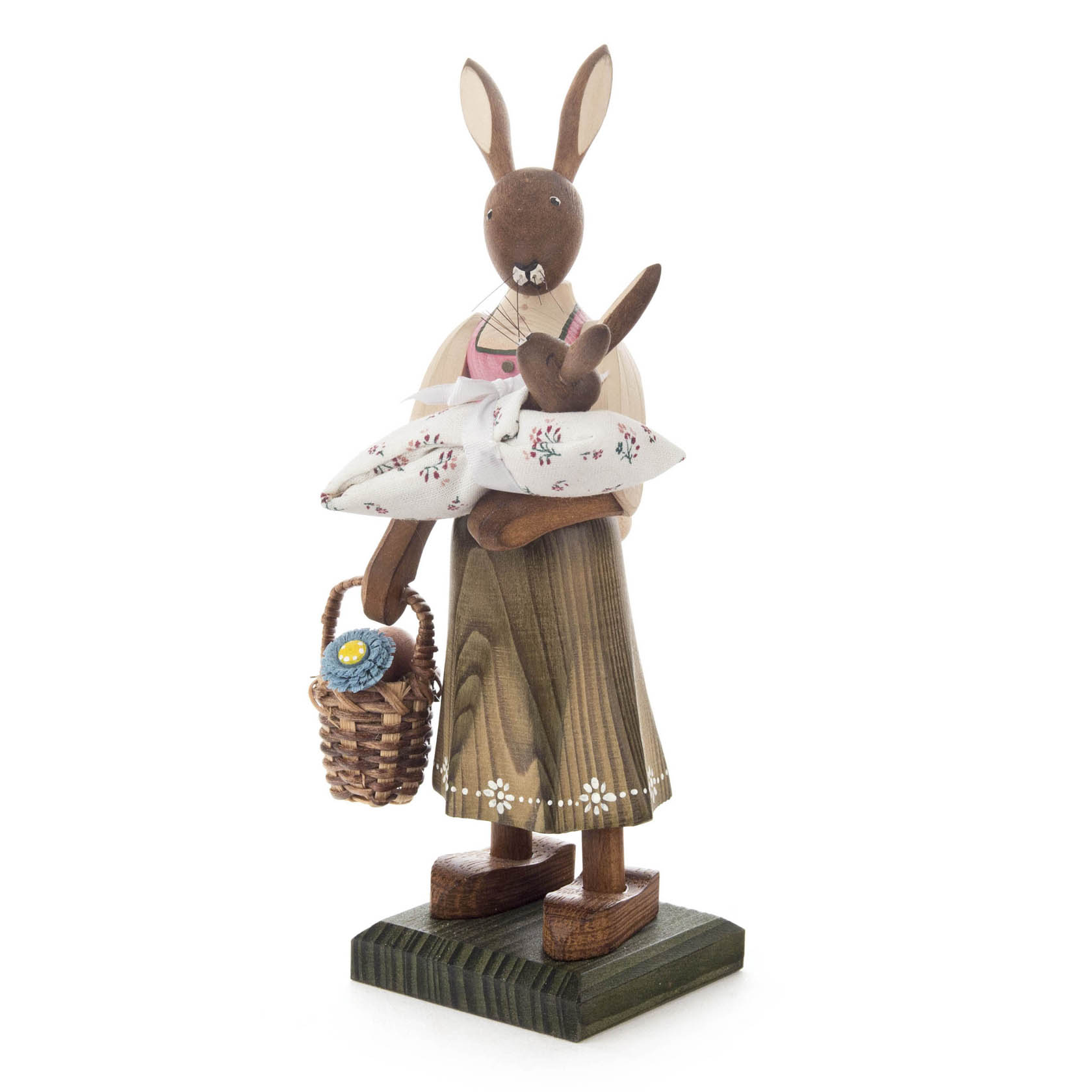 A tall wooden female rabbit figurine holding a baby rabbit wrapped in a blanket, with a small basket with a flower on her arm.