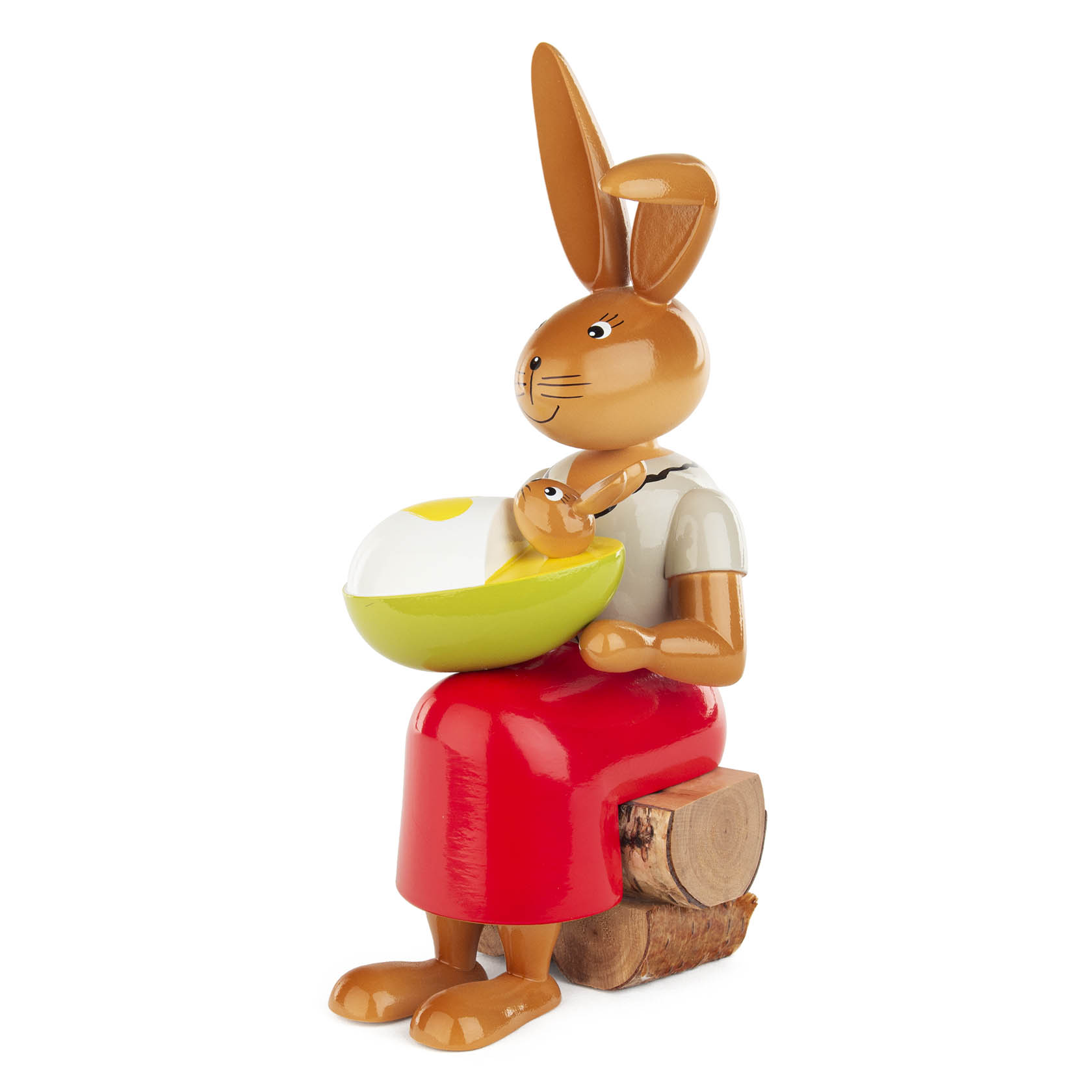 Eine hölzerne Figur einer Häsin, die ein Kind in einem Ei auf dem Schoss hält. Die Häsin trägt einen roten Rock und sitzt auf einem Korken.