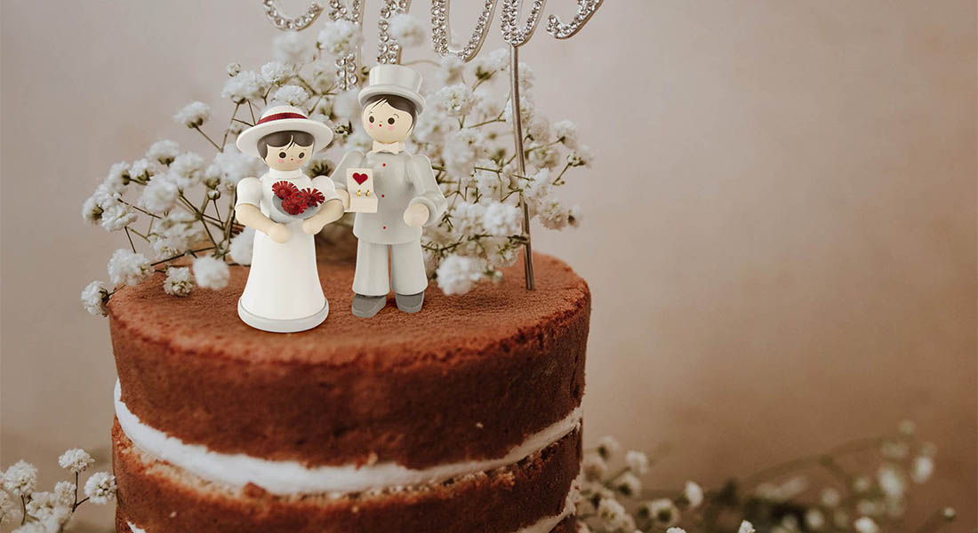 Ein kleines erzgebirgisches Brautpaar aus Holz steht als Dekoration auf einer Hochzeitstorte