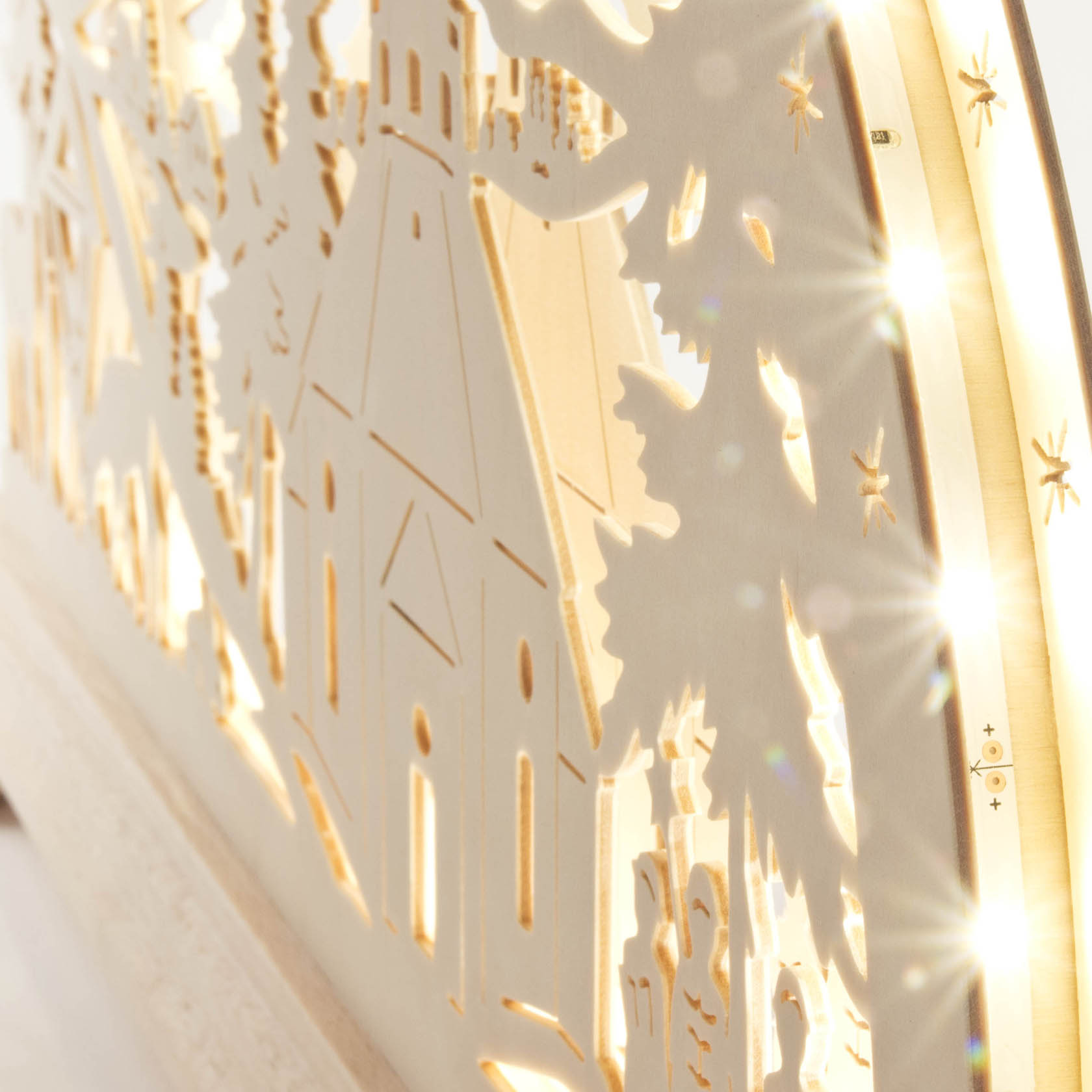 Ein filigraner Schwibbogen zeigt die Seiffener Kirche, umgeben von Bäumen und Figuren, mit LED-Beleuchtung, die warme Lichter wirft.