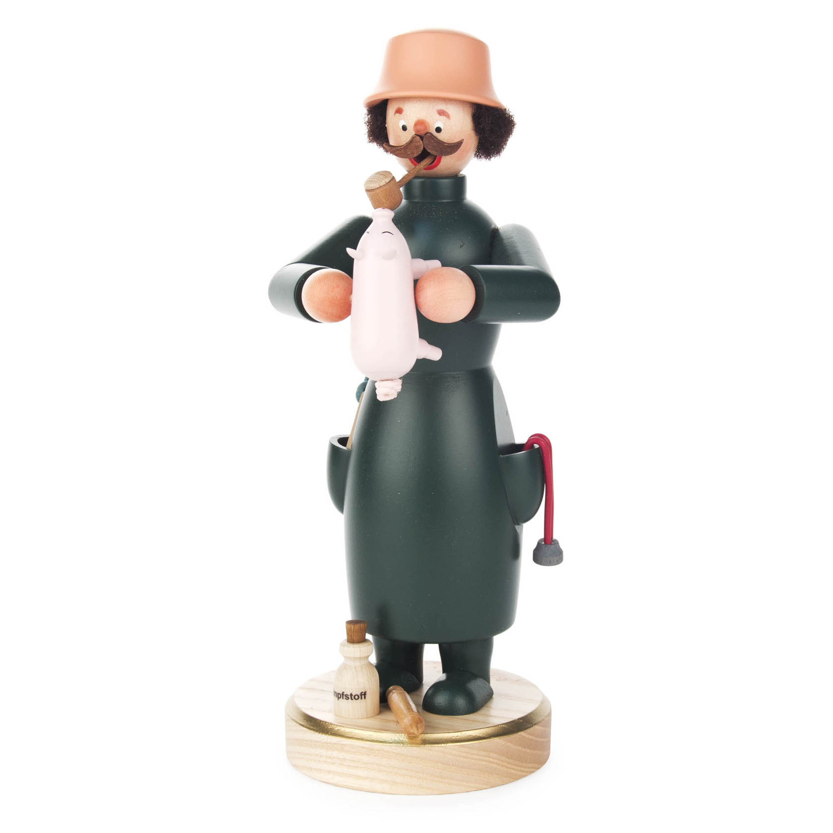 A wooden figurine of a veterinarian in a green coat and hat, holding a piglet. The vet has a curly mustache and is smoking a pipe, with a stethoscope around the neck. A bottle of Schnapps is next to the figure.