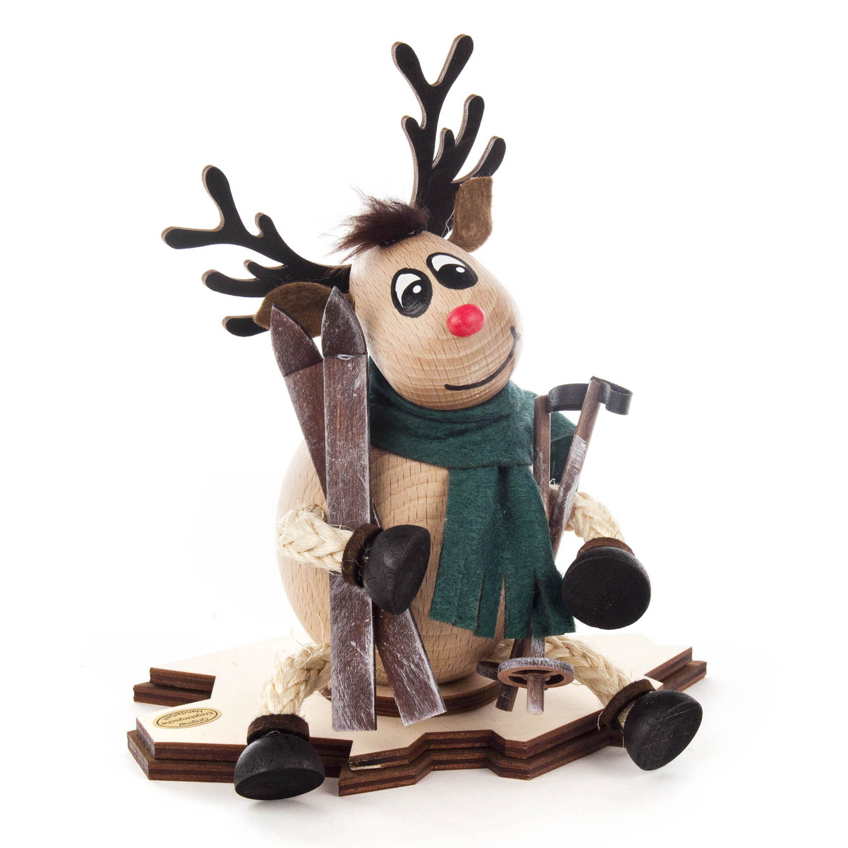 Holzfigur eines lächelnden Elchs mit roter Nase, grüner Schärpe und Skizubehör, sitzend auf einer Holzplatte. im Dregeno Online Shop günstig kaufen