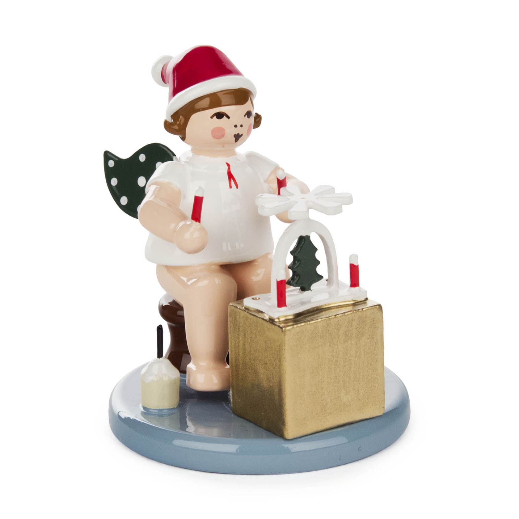 A Christmas angel figurine sitting on a stool, with wings, wearing a Santa hat, holding a small pyramid and surrounded by candles. im Dregeno Online Shop günstig kaufen