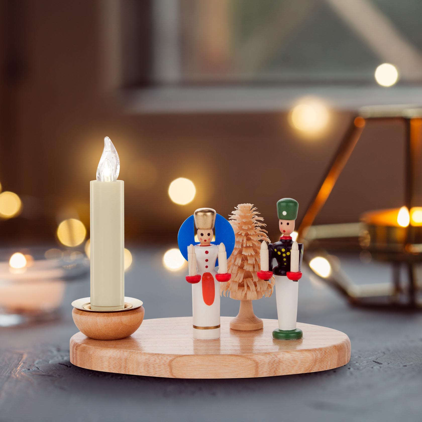 Wooden candle holder with a candle, an angel, a miner, and a small tree on an oval wooden base.