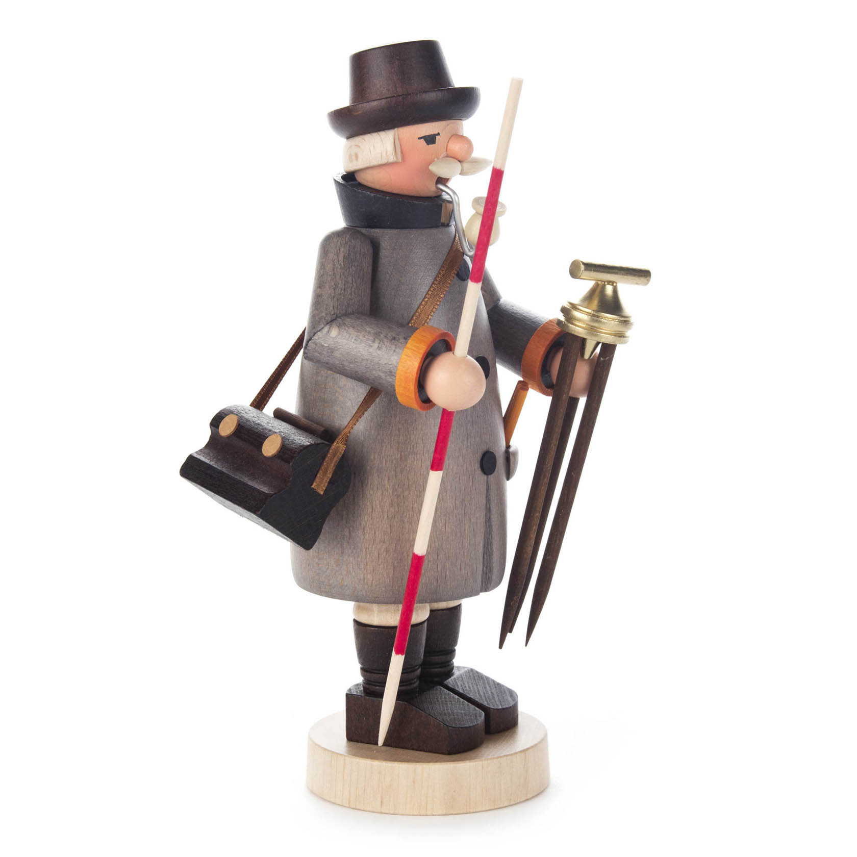 Ein Räuchermann in Gestalt eines Vermessers mit einem grauen Mantel, schwarzem Hut, brauner Tasche, Stab und Messinstrument, stehend auf einem runden Sockel.