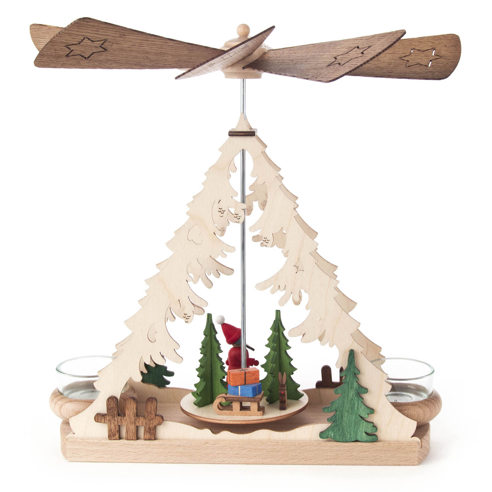 Holzpyramide in Form eines Tannenbaums mit Weihnachtsmannfigur, umgeben von kleinen Bäumen. Zwei Teelichthalter an den Seiten, oben ein Flügelrad.