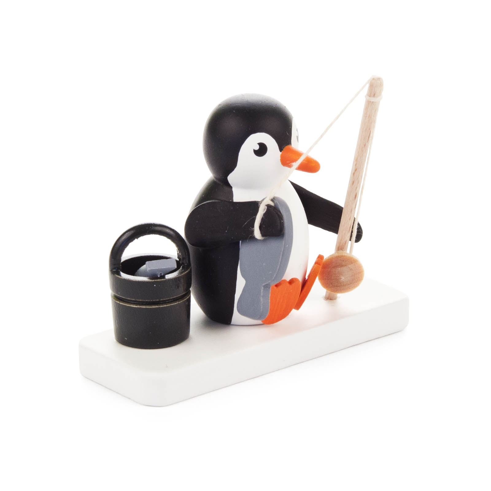 Kleine Pinguin-Figur mit Angelrute, die auf einem weißen Sockel sitzt, neben einem schwarzen Eimer. im Dregeno Online Shop günstig kaufen