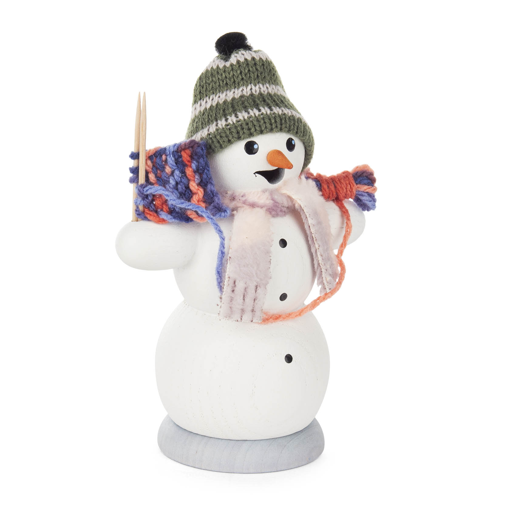 A wooden incense snowman figurine with a green knitted hat, holding knitting needles and a colorful scarf in progress. im Dregeno Online Shop günstig kaufen
