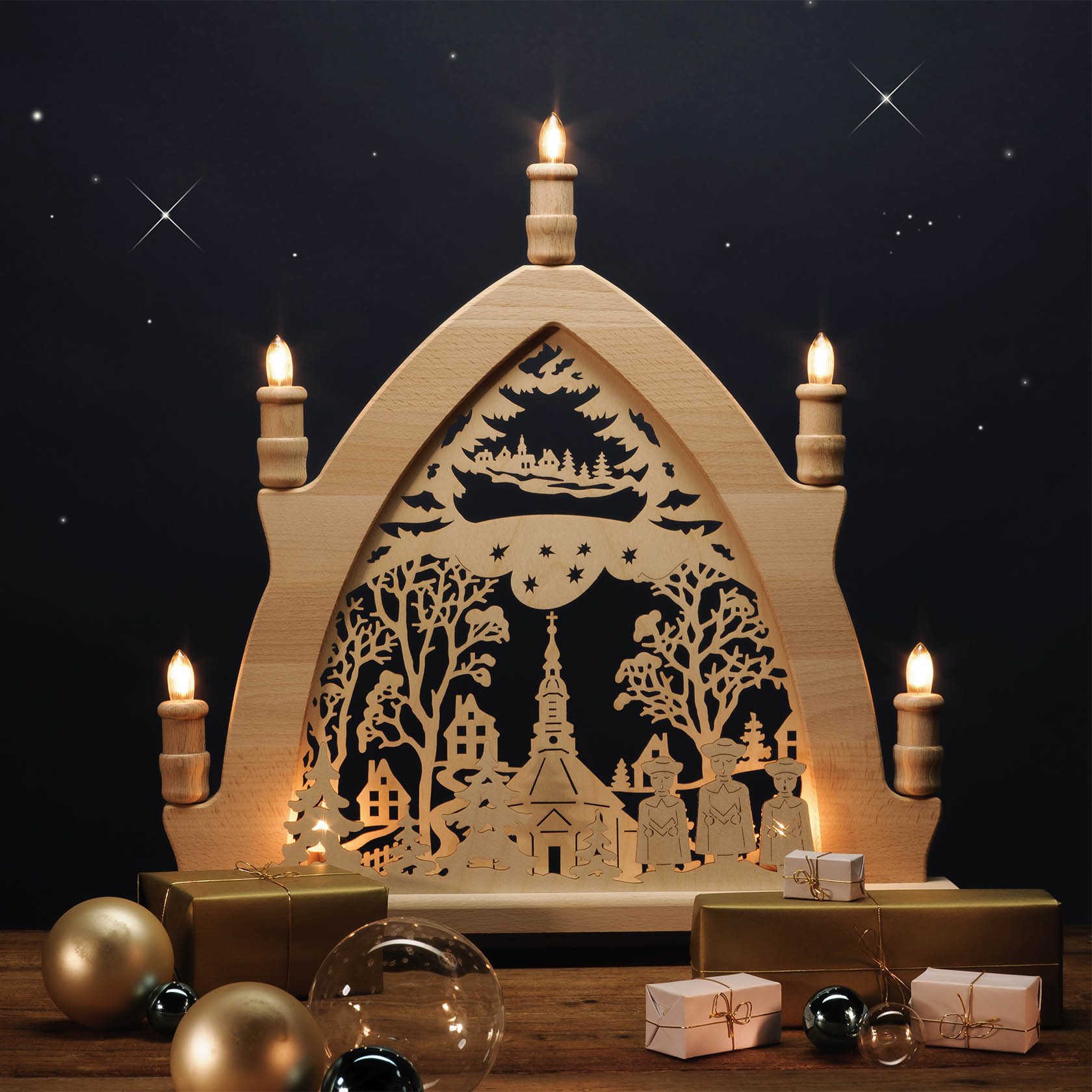 Holzleuchter in Form eines Bogens mit einer filigranen Darstellung der Seiffener Kirche, beleuchtet mit mehreren Kerzen und umgeben von Bäumen und Figuren.