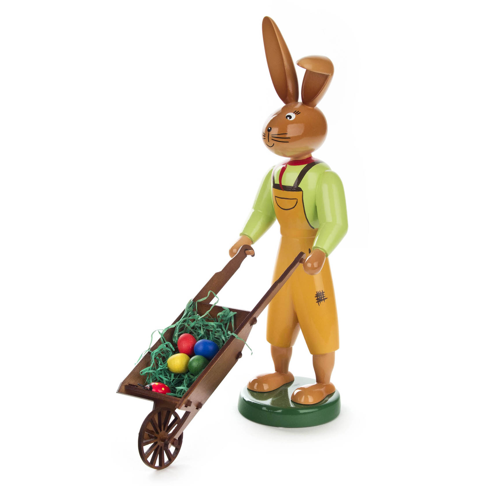 Holzfigur eines Hasen in grüner Jacke und gelbem Overall, der eine Schubkarre mit bunten Ostereiern schiebt.