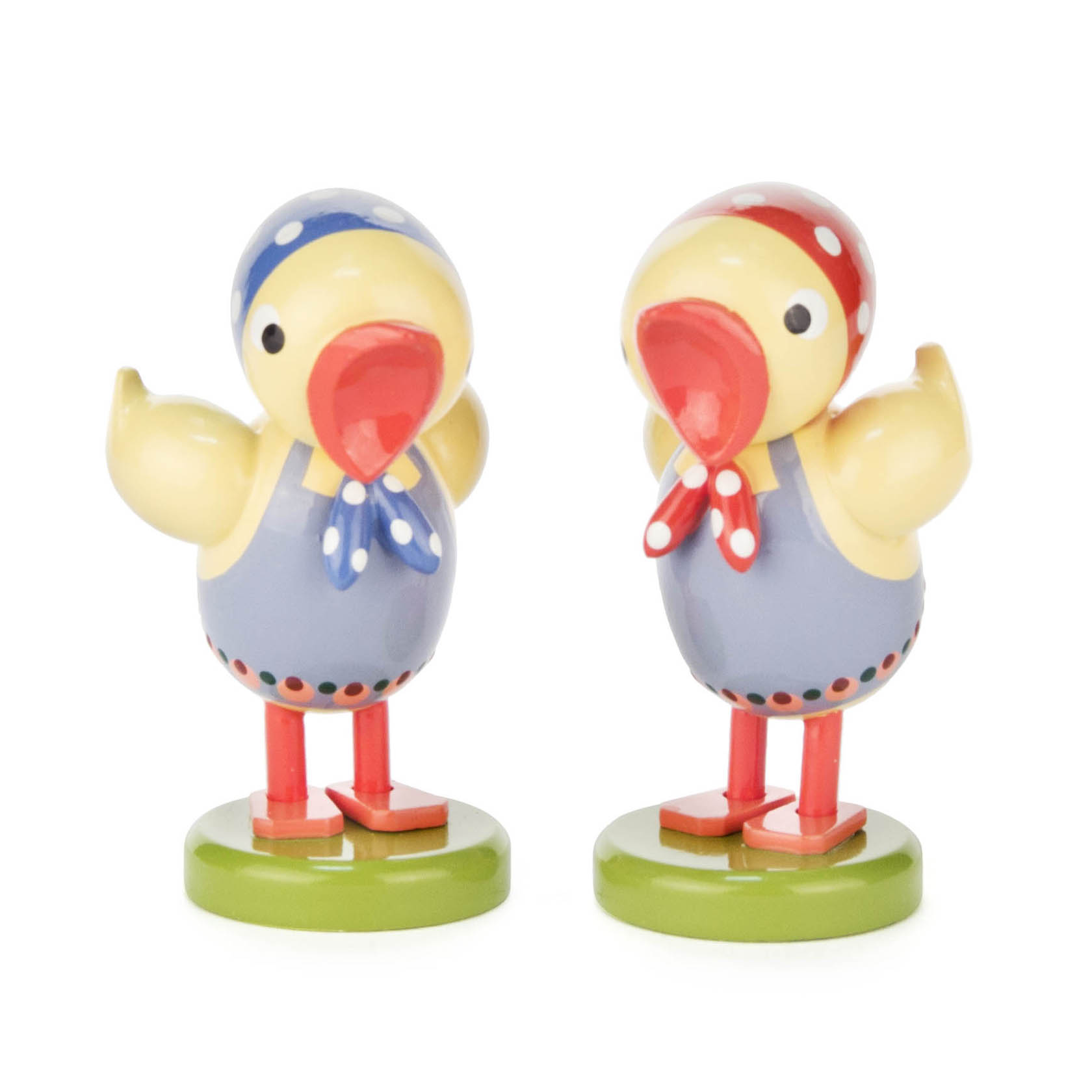 Zwei gelbe Kükenfiguren mit Kopftüchern und Halstüchern, eine trägt blau, die andere rot, auf grünen Sockeln stehend. im Dregeno Online Shop günstig kaufen