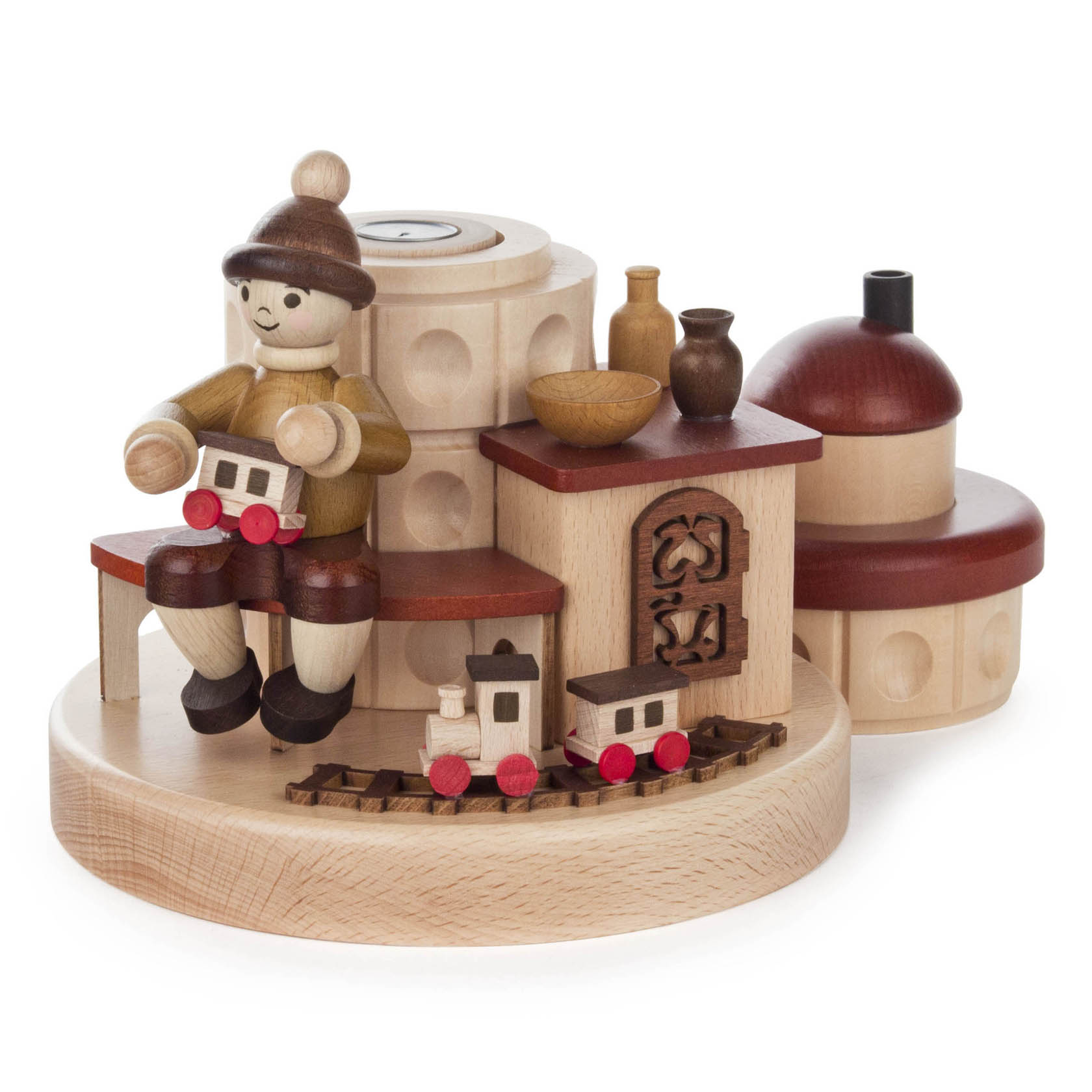 Holzfigur eines Jungen mit brauner Mütze und beigem Oberteil, der auf einer Bank sitzt und eine kleine Holzlokomotive hält. Daneben ein runder, ornamentierter Räucherofen.