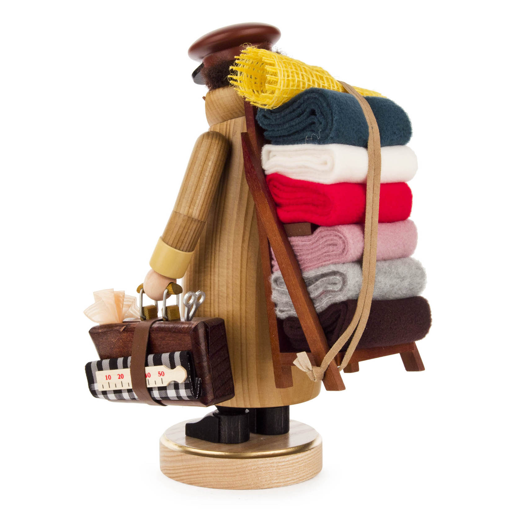 A wooden incense smoker figurine of a fabric merchant, seen from the side. The figure carries a suitcase and has a stack of colorful fabric rolls on its back.