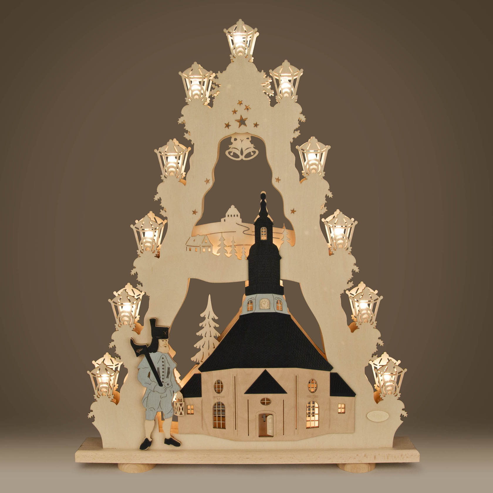 Ein Schwibbogen mit der Darstellung der Seiffener Kirche, umgeben von LED-Lichtern in Sternform und einem gedrechselten Bergmann.