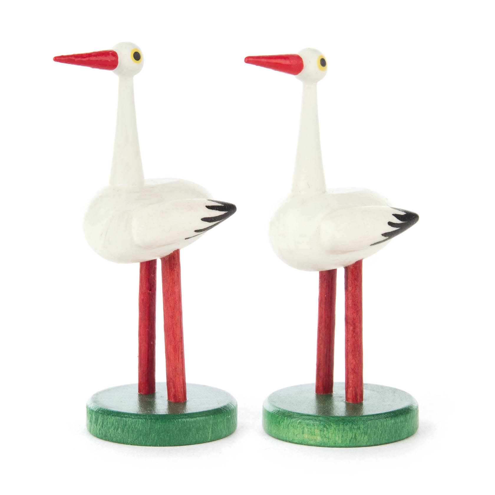 Zwei weiße, hölzerne Storchenfiguren mit roten Schnäbeln und Beinen stehen auf grünen Sockeln. im Dregeno Online Shop günstig kaufen
