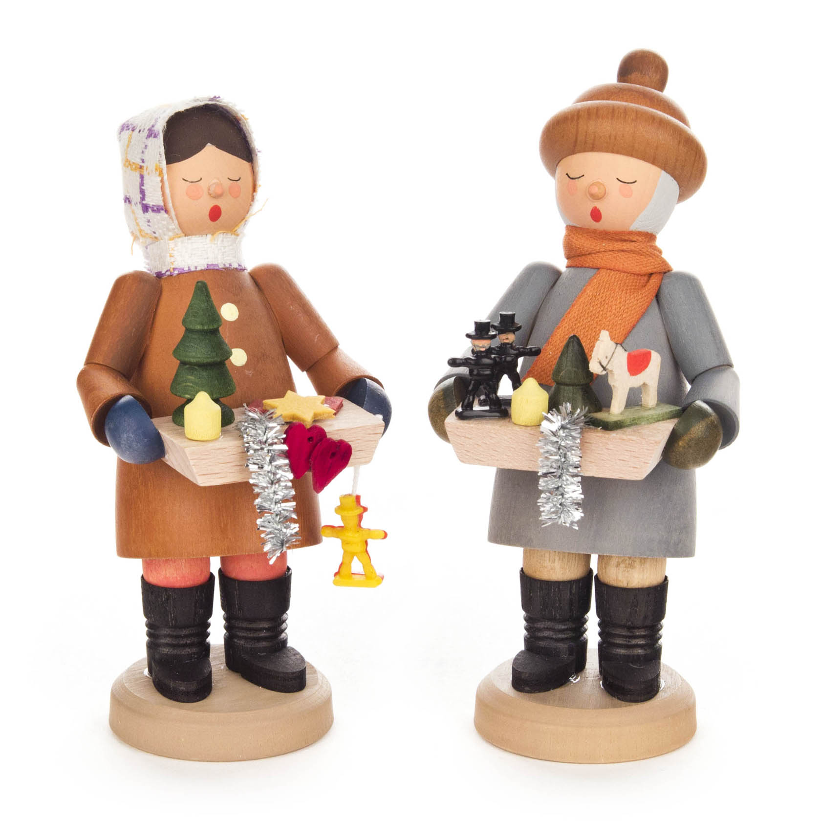 Zwei bemalte Holzfiguren, die als Striezelkinder verkleidet sind, halten jeweils ein Tablett mit Miniaturen von Weihnachtsbäumen, Spielzeugen und Geschenken. im Dregeno Online Shop günstig kaufen