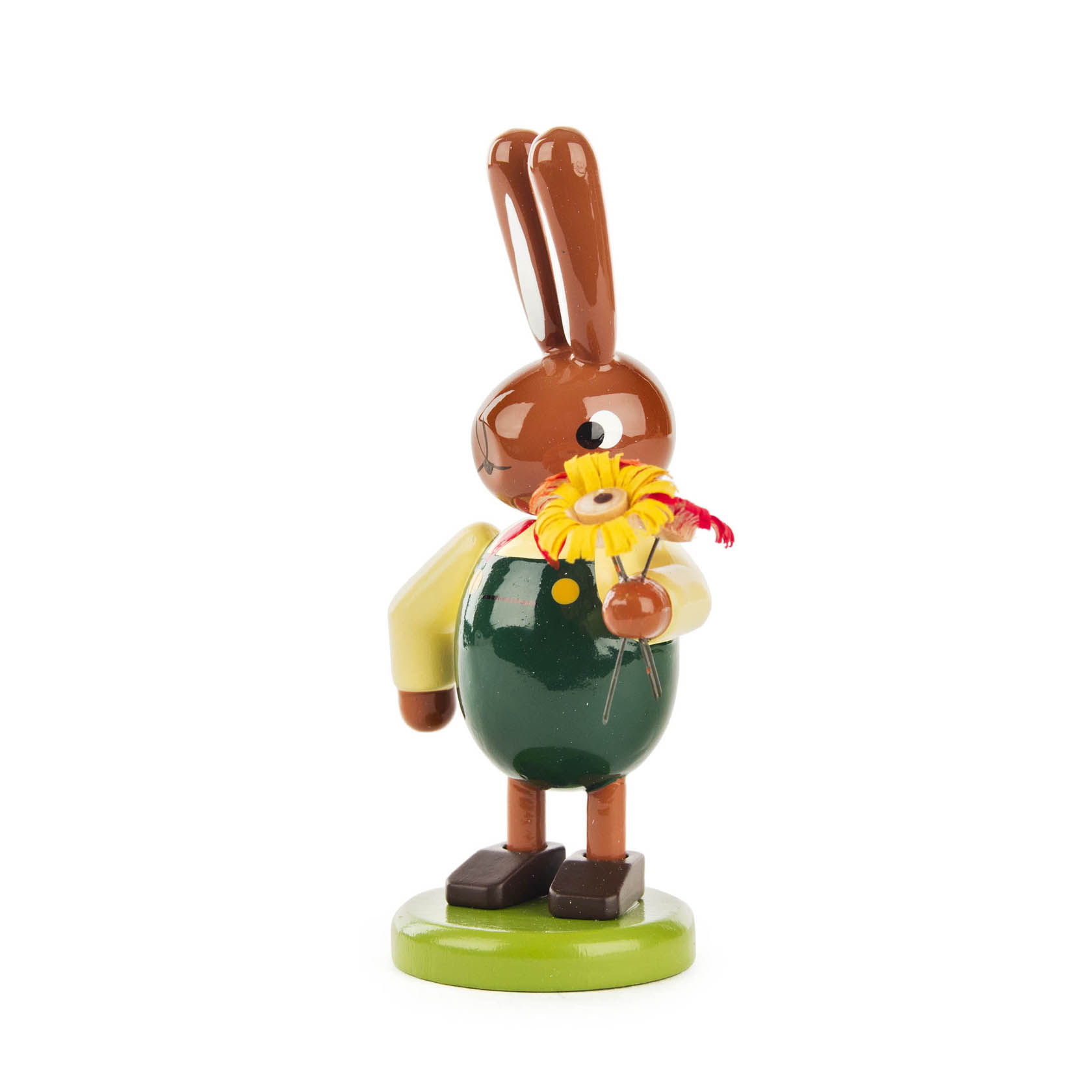 Kleines Holzfigürchen eines Hasen in grüner Latzhose, hält bunte Blumen in der linken Pfote.