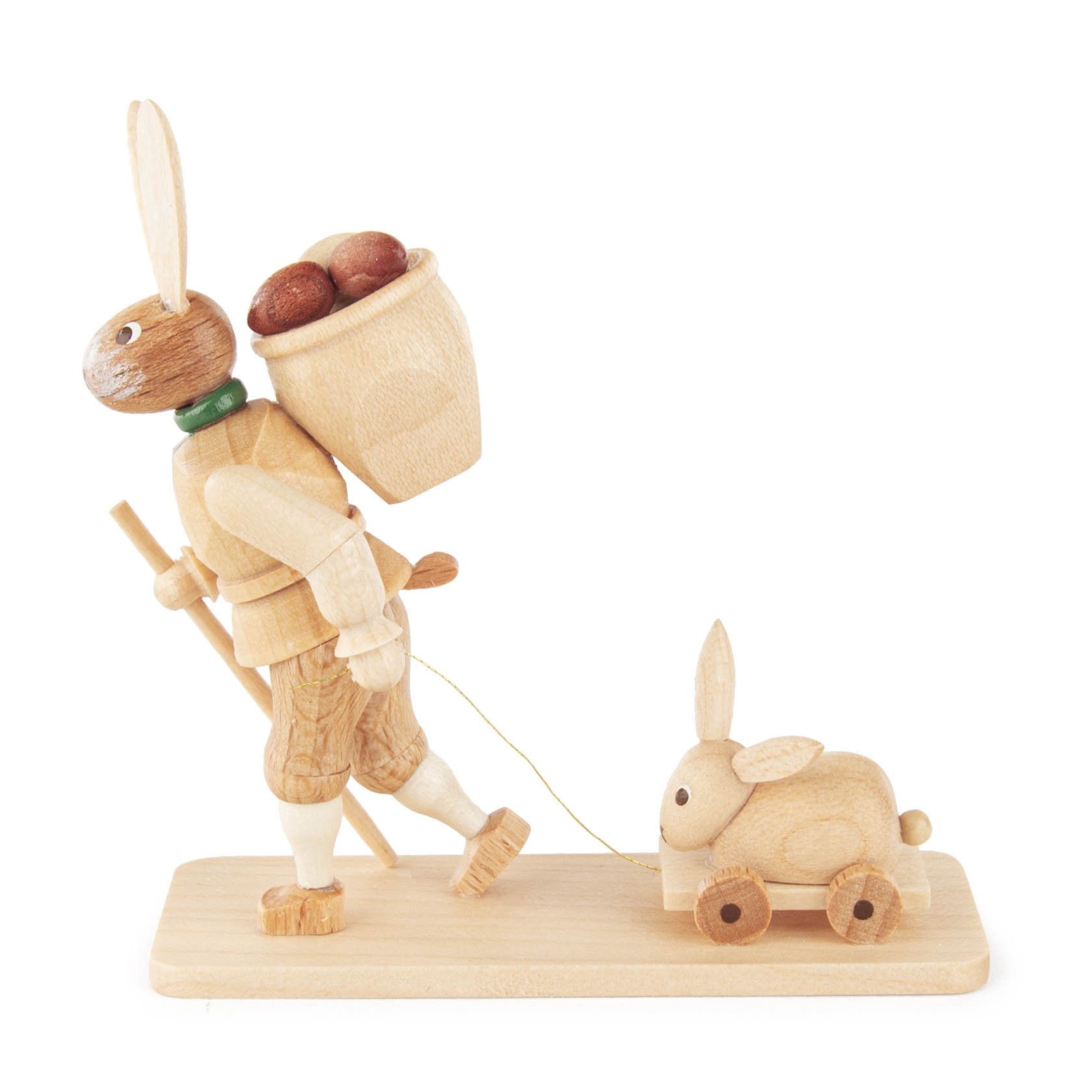 Holzfigur eines Osterhasen mit einem Korb auf dem Rücken, der Eier enthält. Der Hase steht auf einem Sockel und zieht einen hölzernen Hasen auf Rädern.