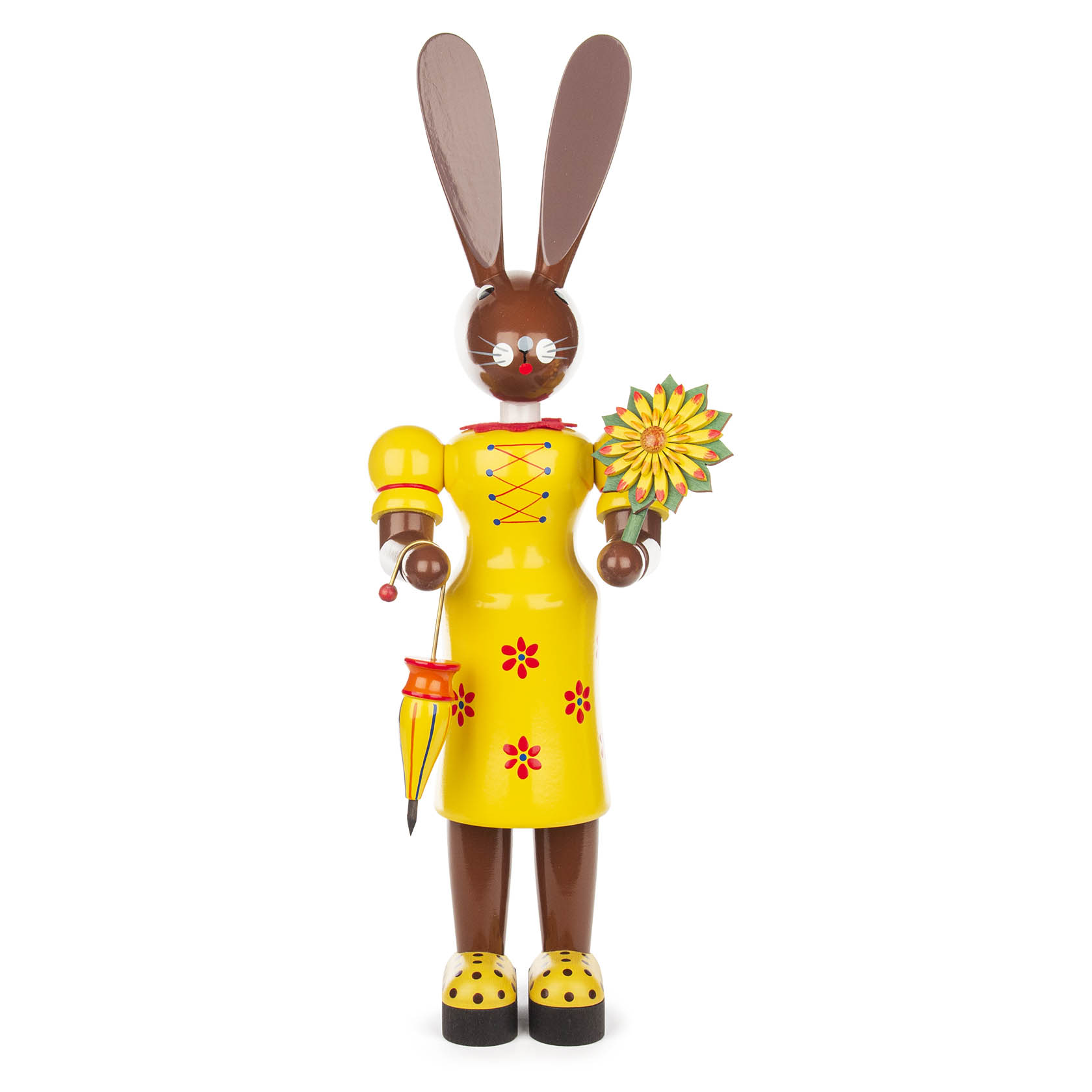 A tall, brown wooden female bunny figurine wearing a bright yellow dress with red flower patterns, holding a decorative flower and an umbrella.
