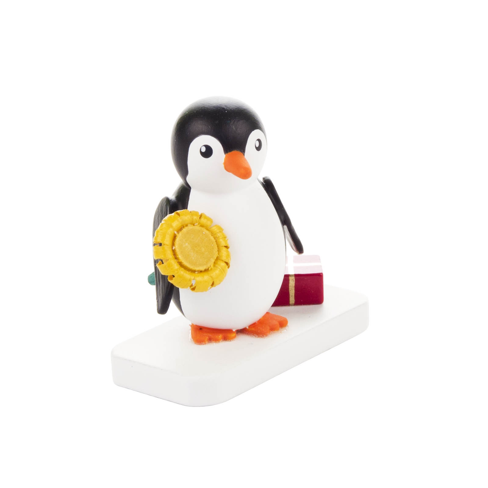 Eine niedliche Pinguin-Figur mit orangefarbenem Schnabel und Füßen hält eine gelbe Sonnenblume und ein kleines rotes Geschenk auf einem weißen Sockel. im Dregeno Online Shop günstig kaufen