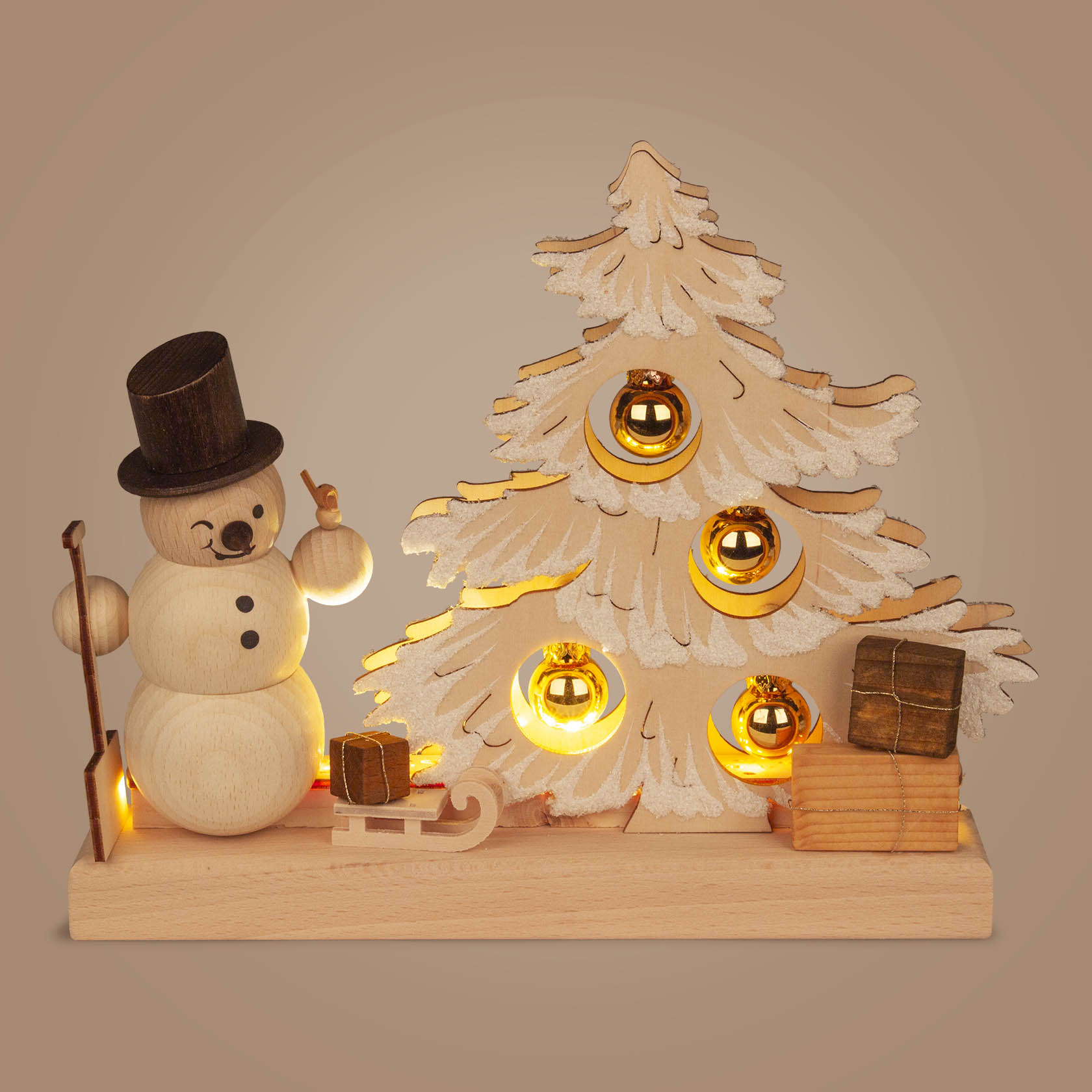 Kleines Holz-Dekor mit beleuchtetem Tannenbaum, drei goldenen Kugeln, einem Schneemann mit Zylinder und Stock, sowie einem Schlitten mit Geschenken.