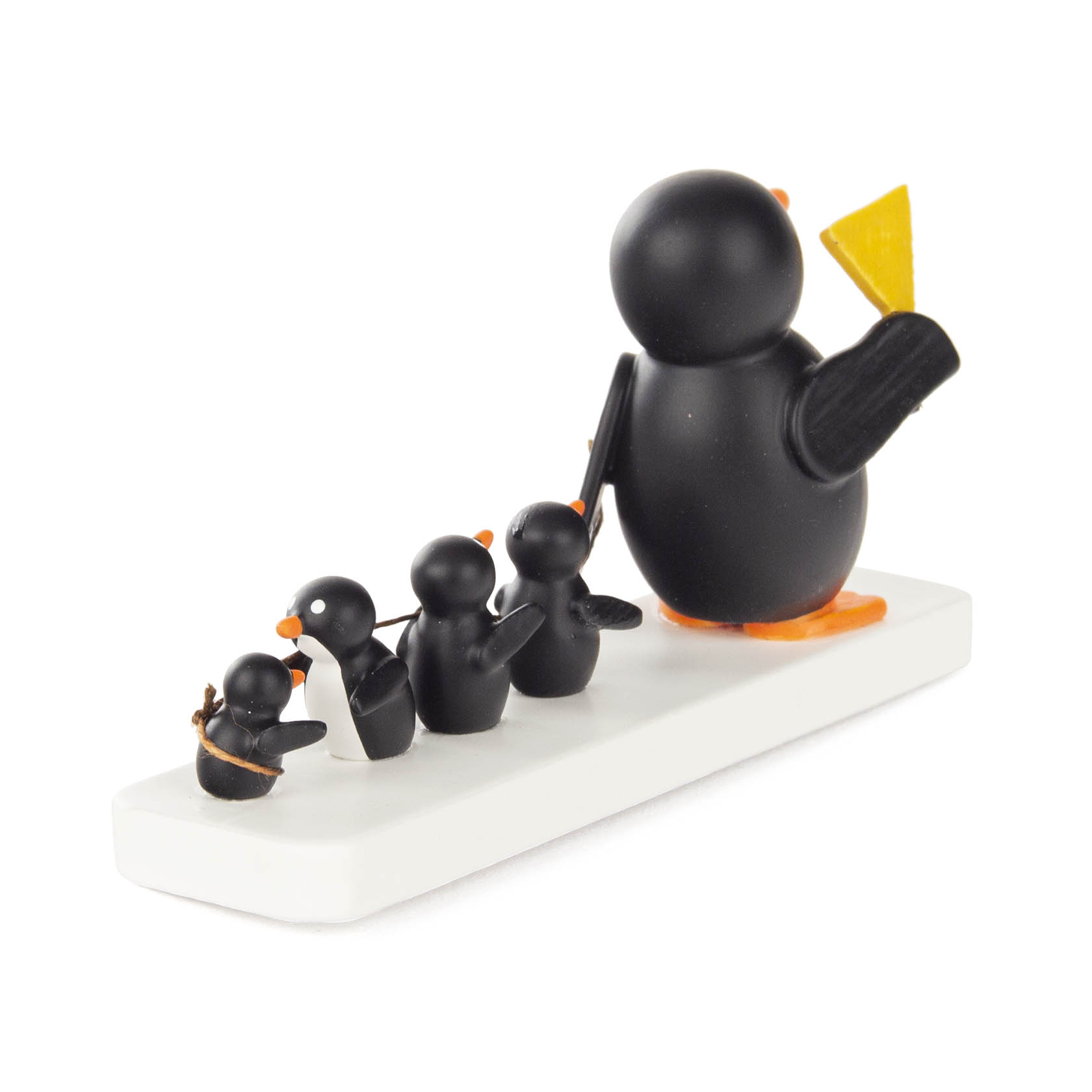 Holzfiguren von einem großen Pinguin mit gelbem Fähnchen, gefolgt von drei kleineren Pinguinen, die durch ein Seil verbunden sind.