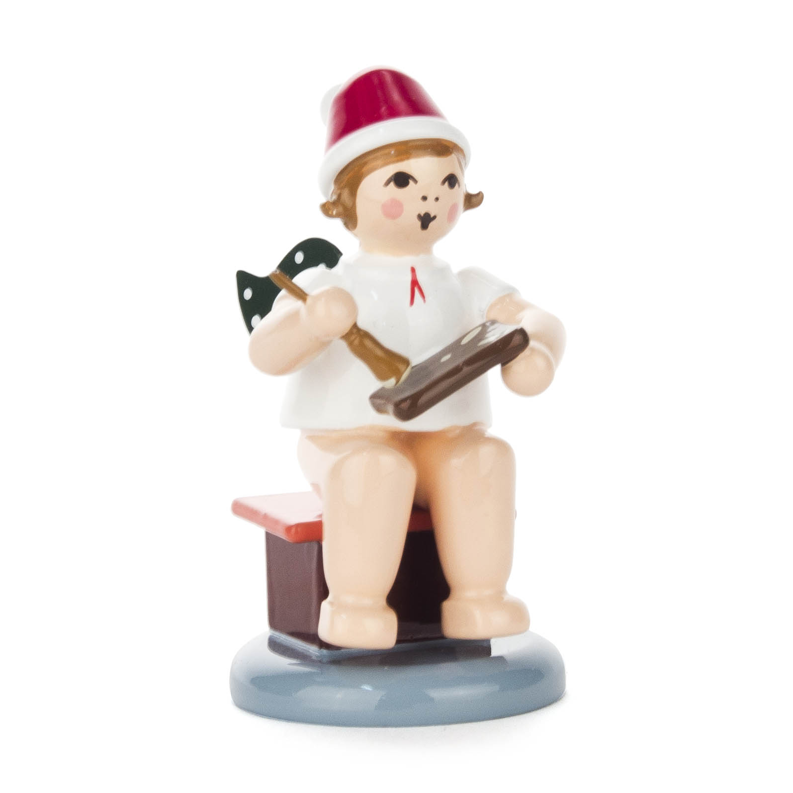Figur eines sitzenden Engels mit weißen Flügeln, roter Mütze und Pfefferkuchen in der Hand. im Dregeno Online Shop günstig kaufen